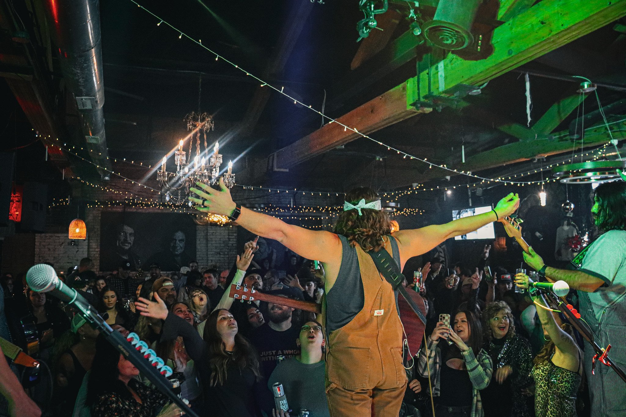 Musician with arms outstretched facing an energetic crowd at a live concert hosted by Lost Street Records.