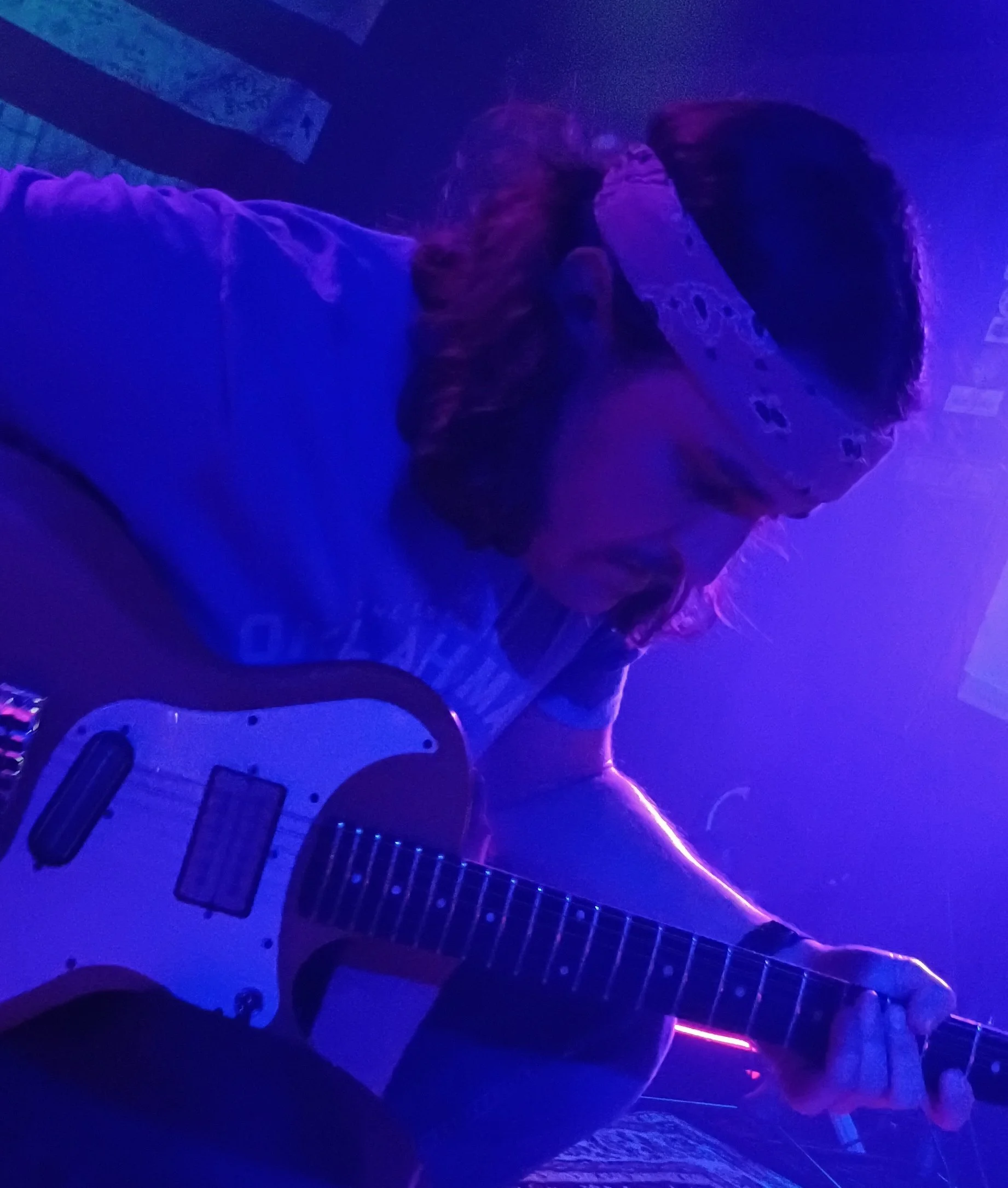 Musician playing an electric guitar under moody blue studio lighting during a life concert recorded by Lost Street Records.