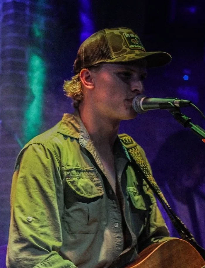 Lost Street Records co-founder and music producer Jake Jankas singing live on stage while playing a guitar.