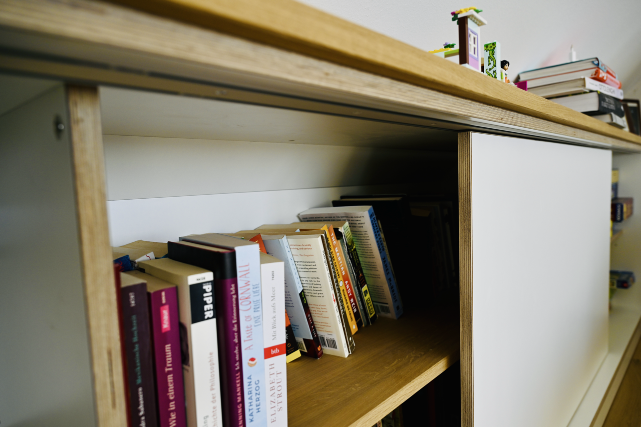 Bücherregal mit Büchern, einige sind horizontal und andere vertikal angeordnet.