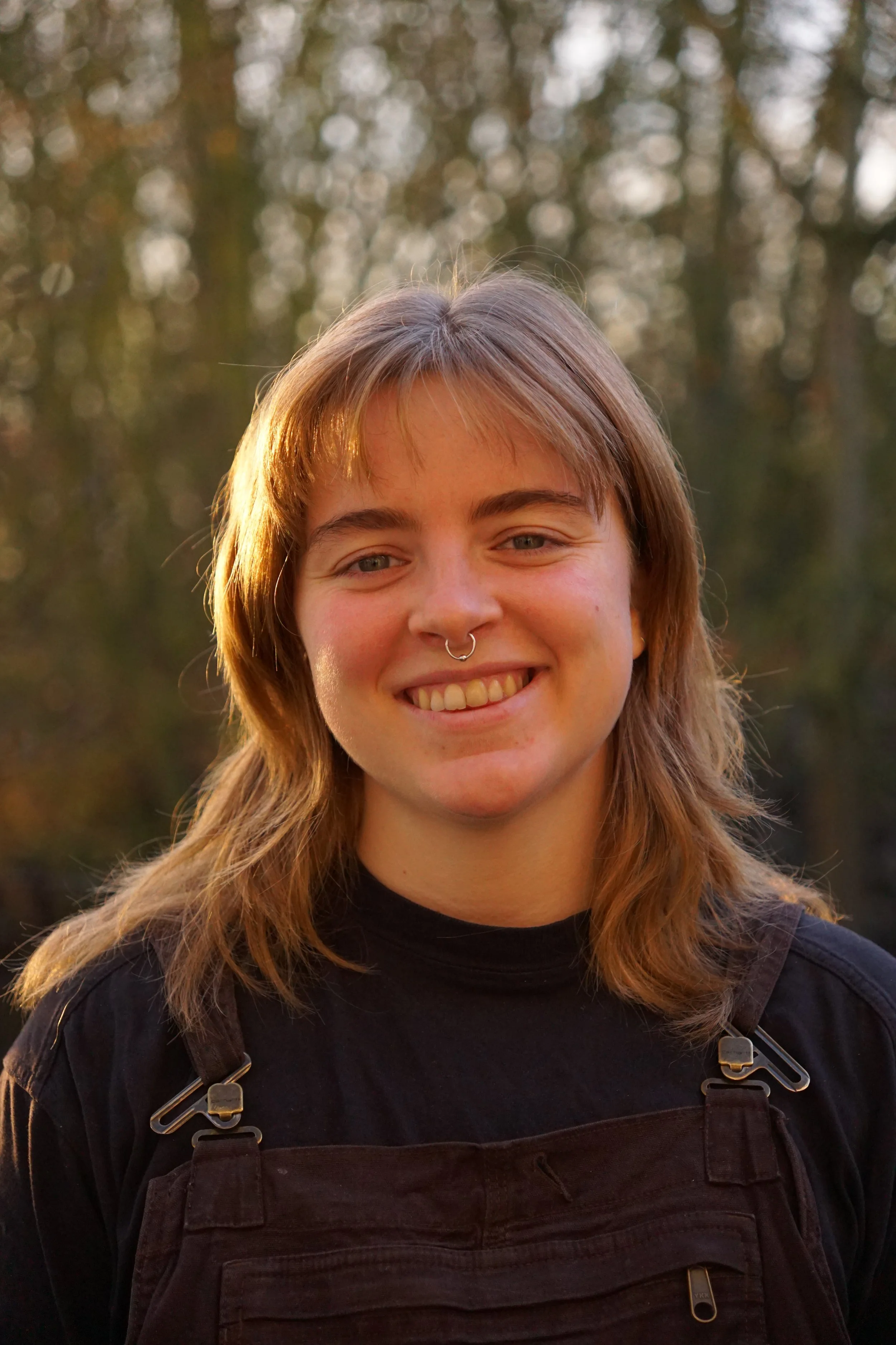 Junge Frau mit braunen Haaren, dunkler Kleidung