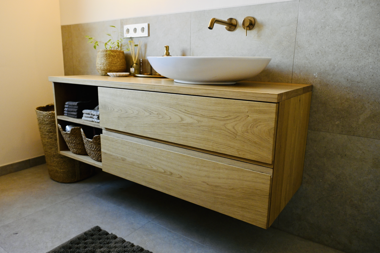Moderner Waschtisch aus hellem Holz mit weißer Waschschale und goldenem Wasserhahn in einem Badezimmer
