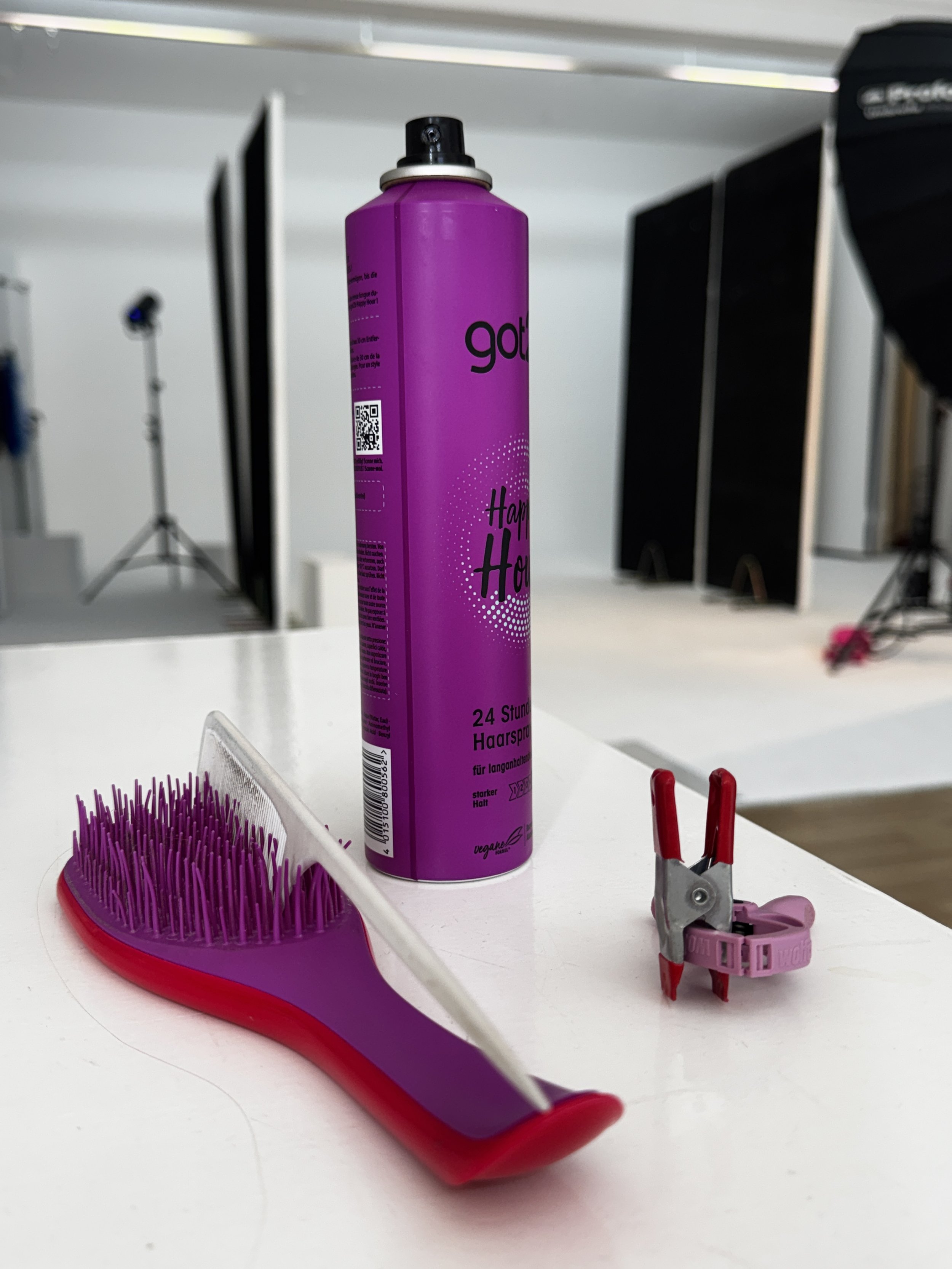 Haarglätterbürste, Haarspray und Haarspangen auf weißem Tisch.