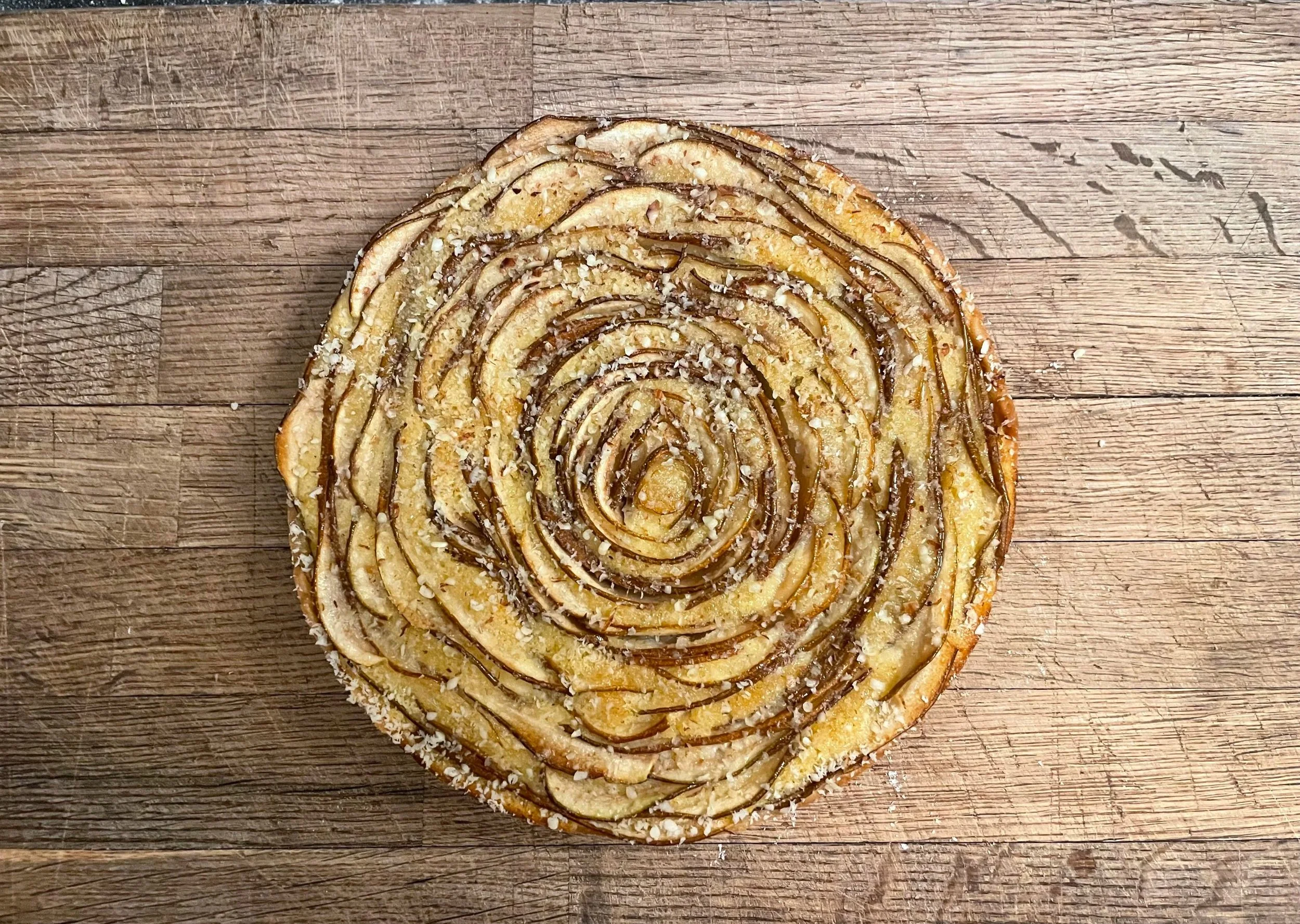Pear tart with sliced pears arranged in a circular pattern, almond praline and topped with salted almond sorbet on the side.