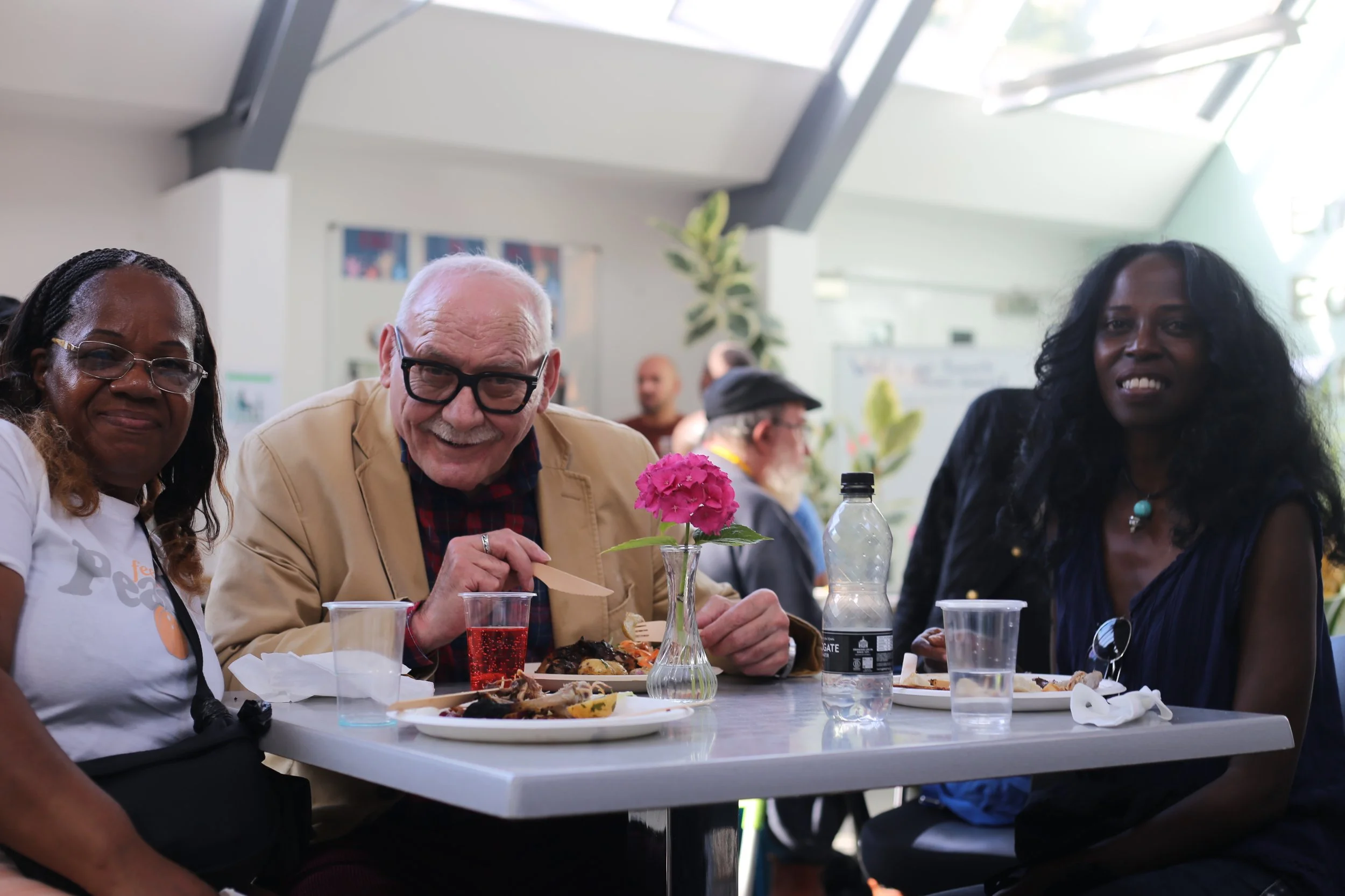 Three people sitting at a table enjoying a meal at an indoor event.
