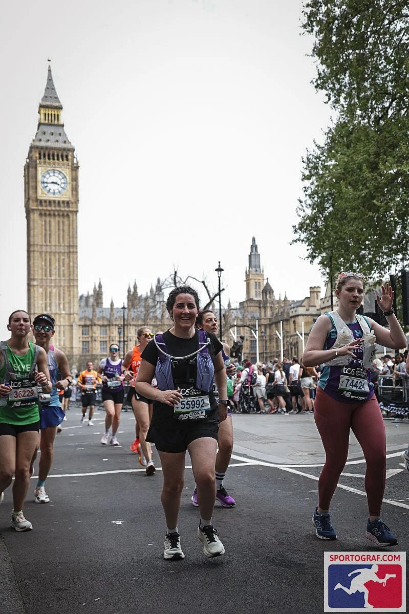 People participating in a marathon running past Big Ben in London, with runners and spectators visible.