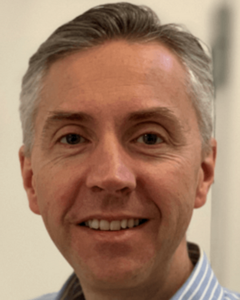 Close-up of a smiling man with gray hair in a collared shirt.