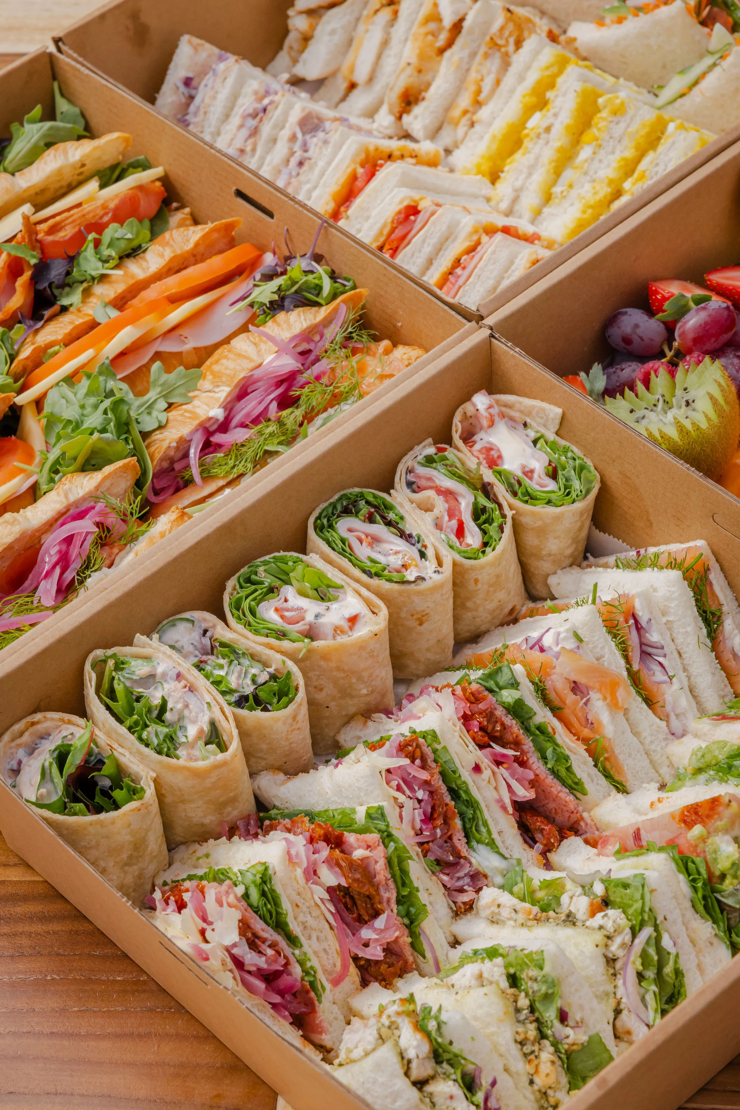 Assorted corporate catering boxes including sandwiches, wraps and savoury filled croissants