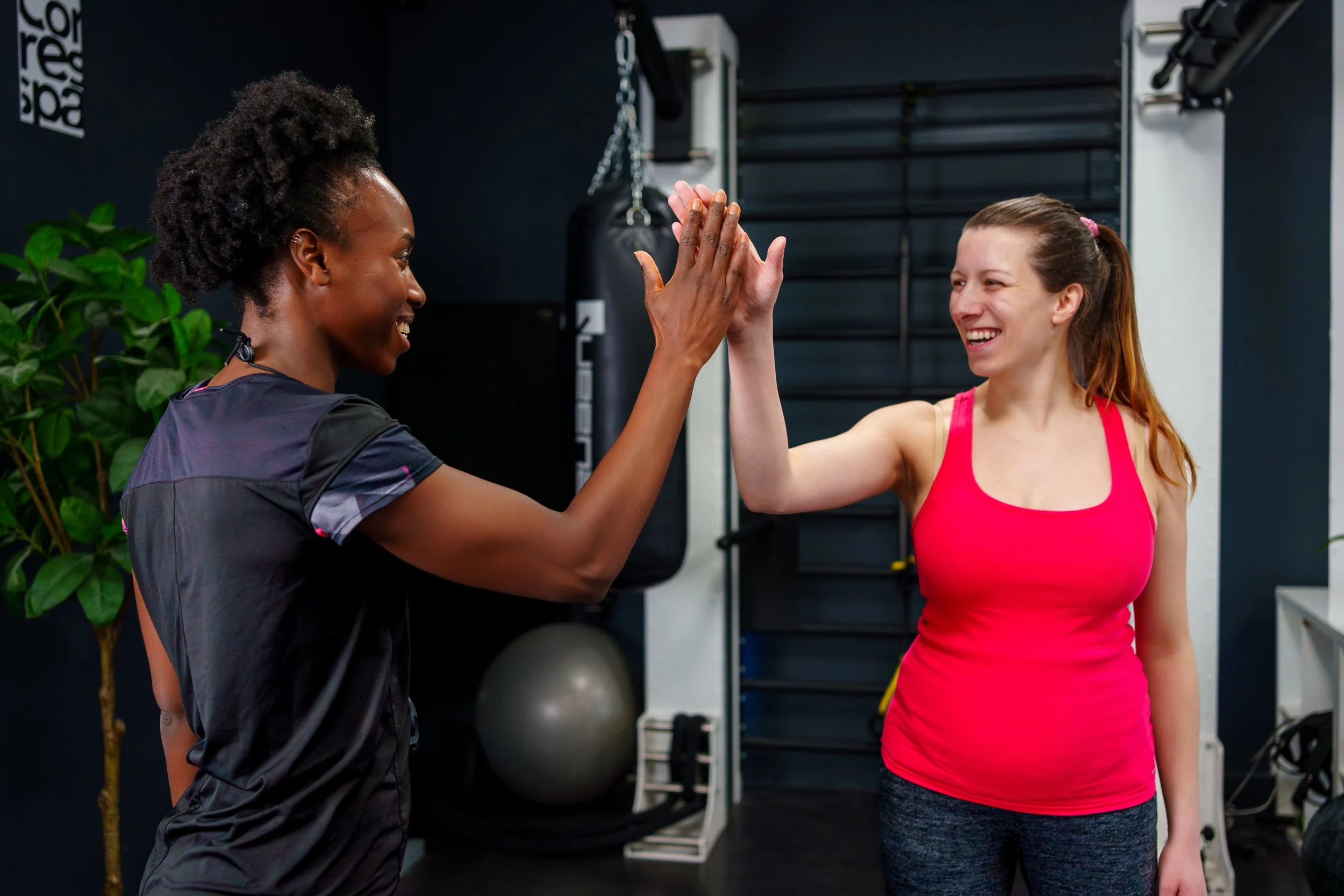 Deux femmes s'engueulant dans une salle de sport, faisant un high five.