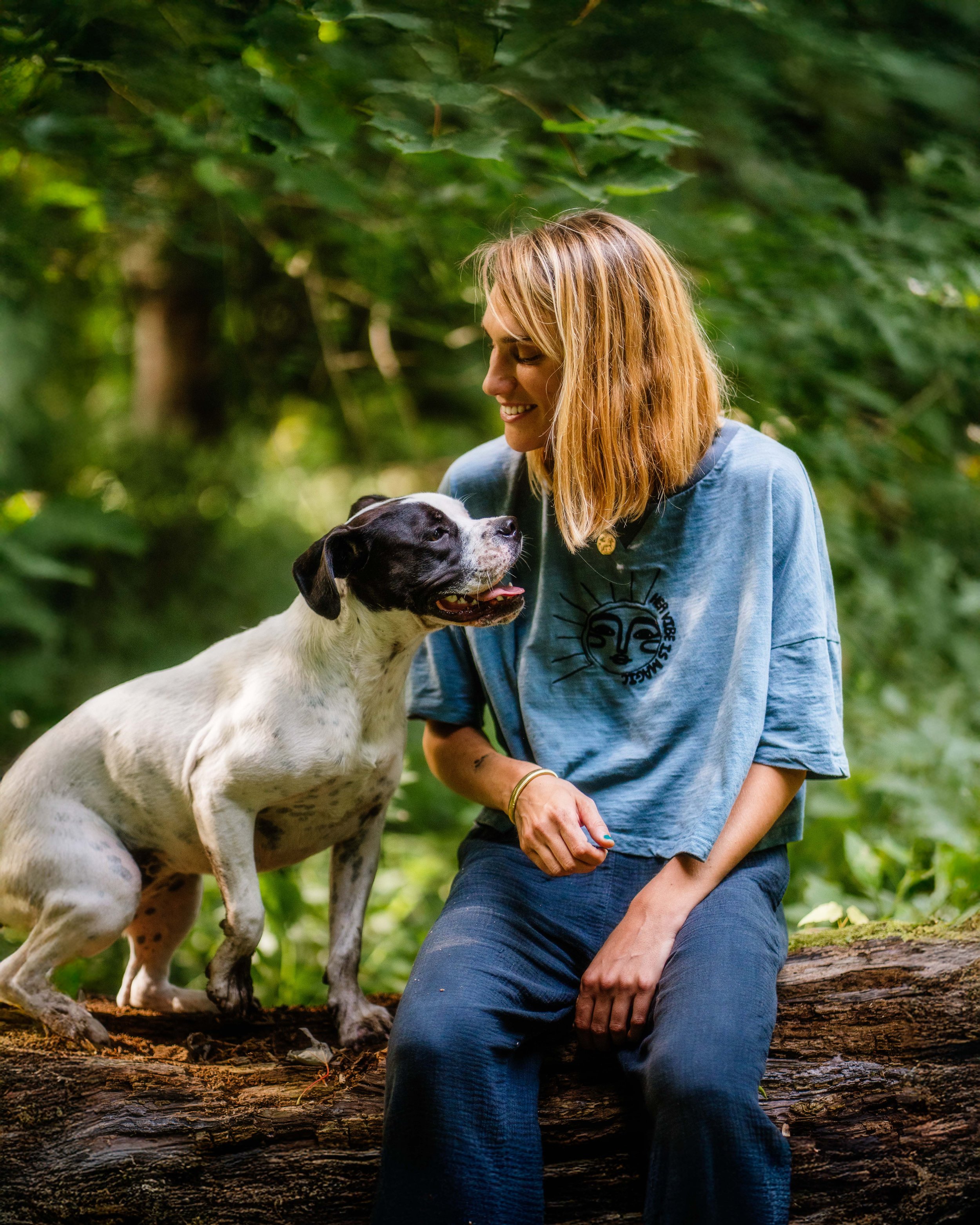 Une femme avec un chien noir et blanc dans une forêt