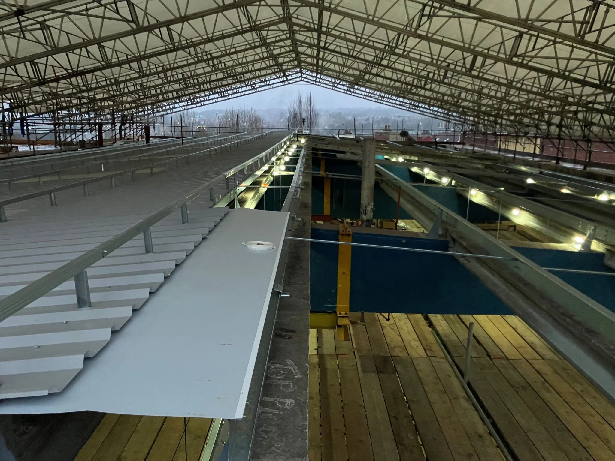 Under construction roof framework with scaffolding and wooden planks, view from above in a building site.