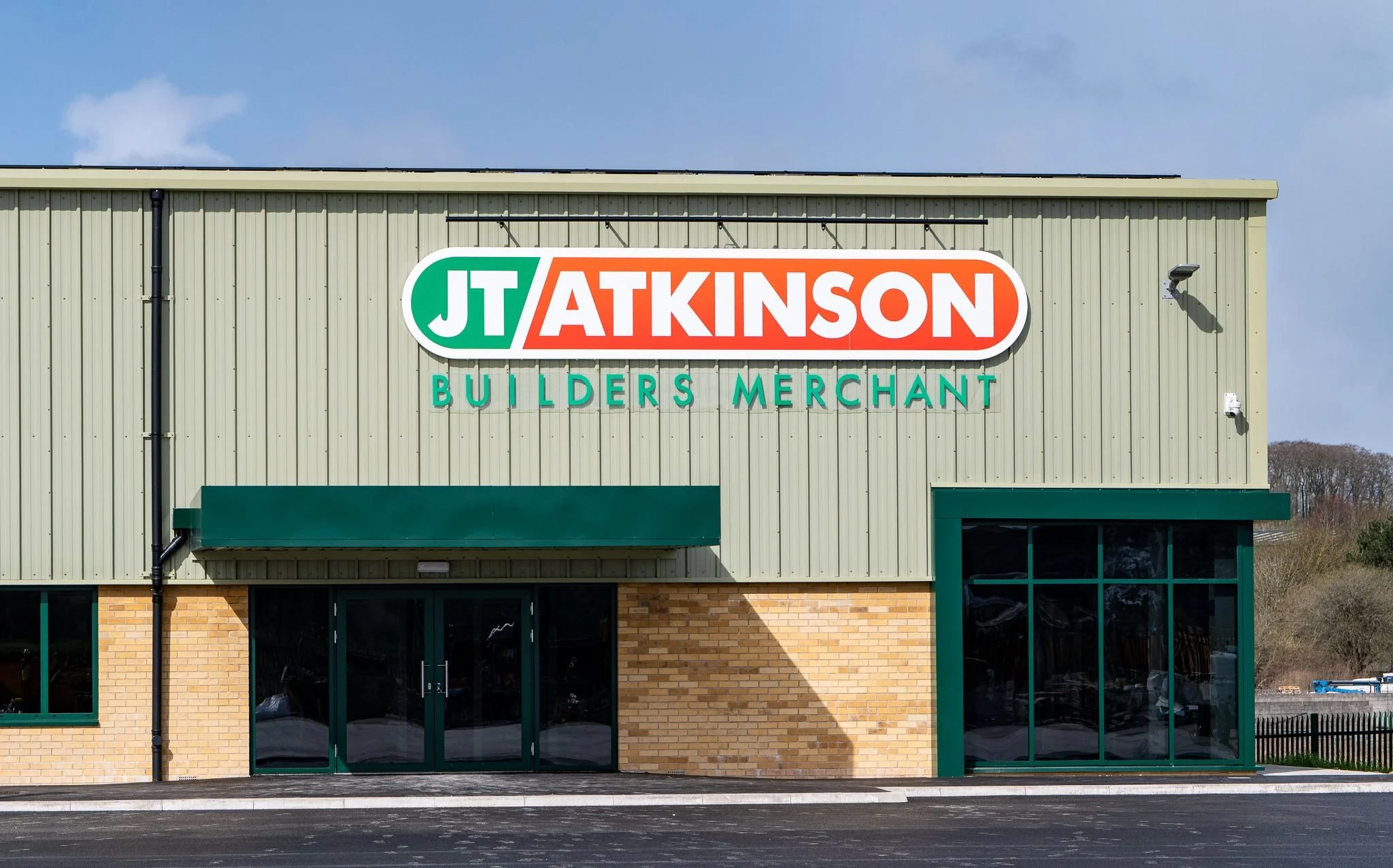 Building exterior with a sign that reads 'JT Atkinson Builders Merchant' in green, orange, and white colors.