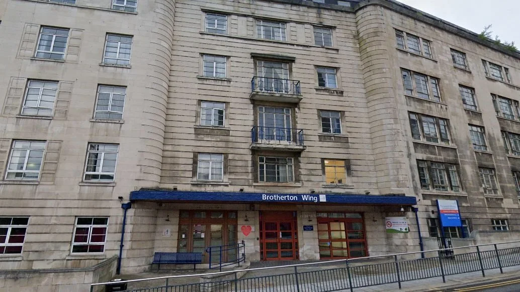 Exterior view of a beige stone building with multiple windows and small balconies, labeled 'Brotherton Wing' at the entrance.