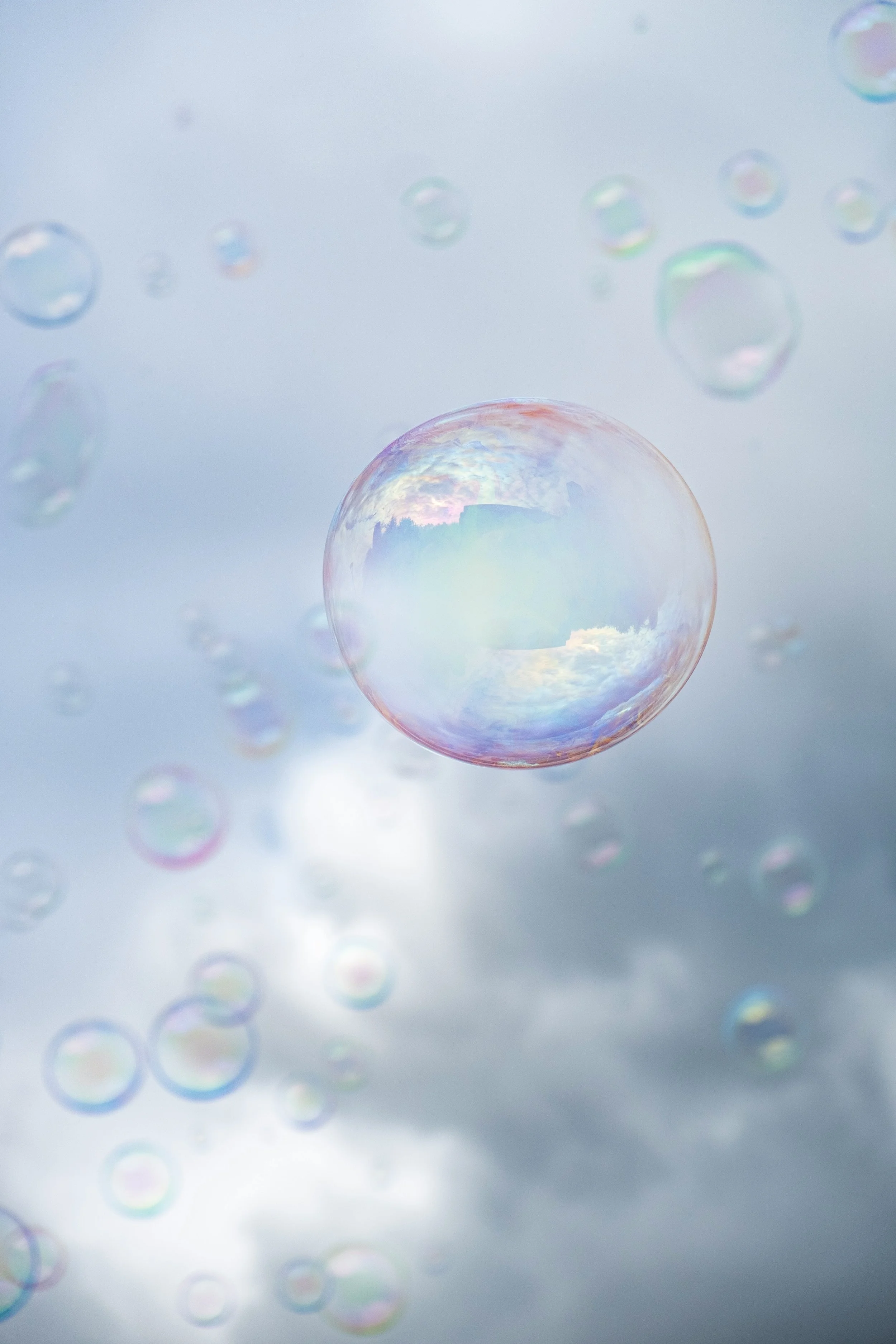 Multiple soap bubbles floating against a cloudy sky.