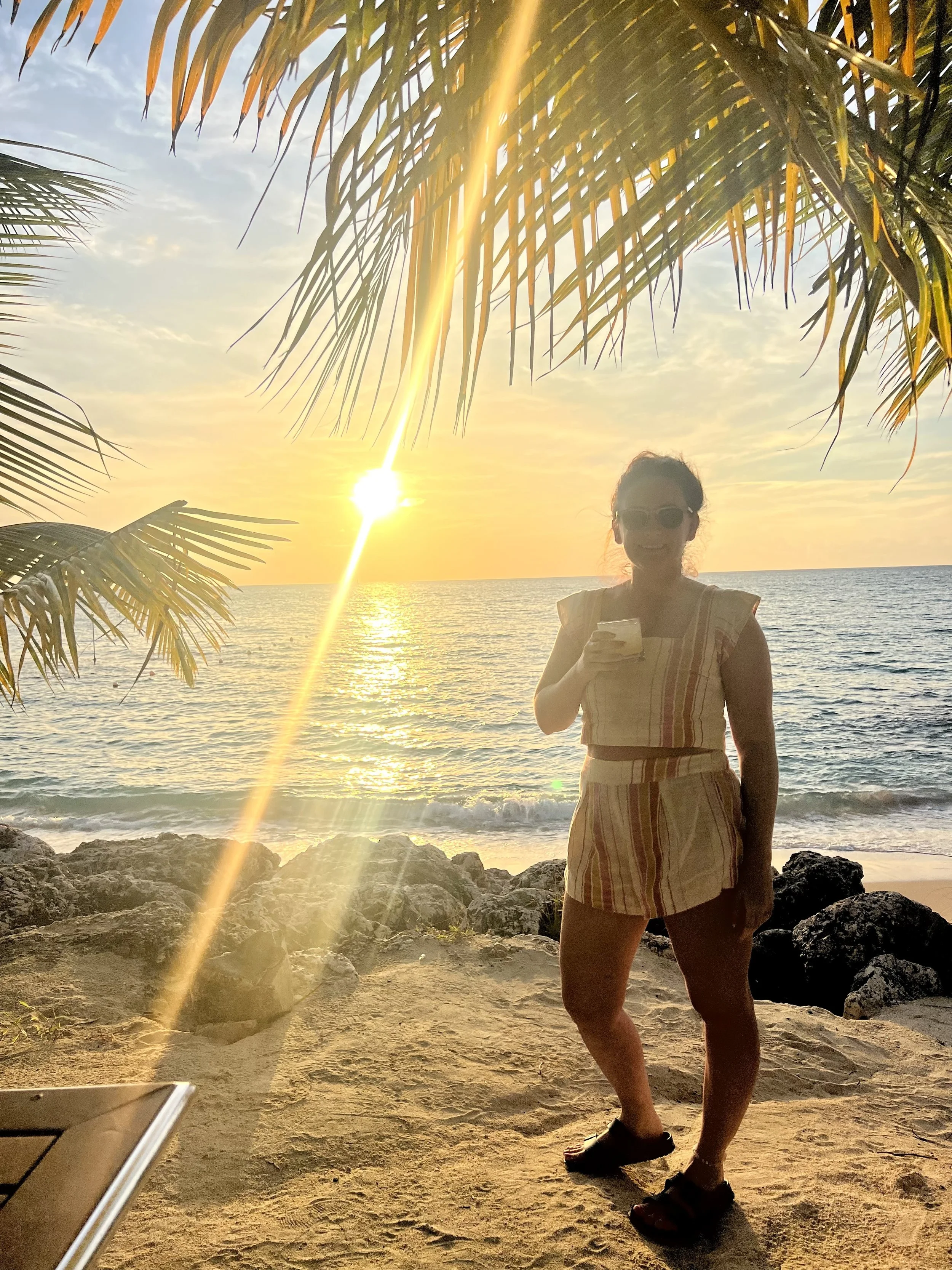 Lady standing on the beach in Barbados as the sunsets behind.