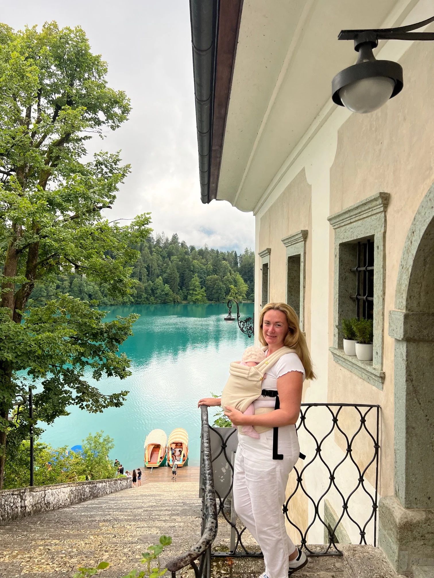 Mum holding baby in sling with Lake Bled in the background.