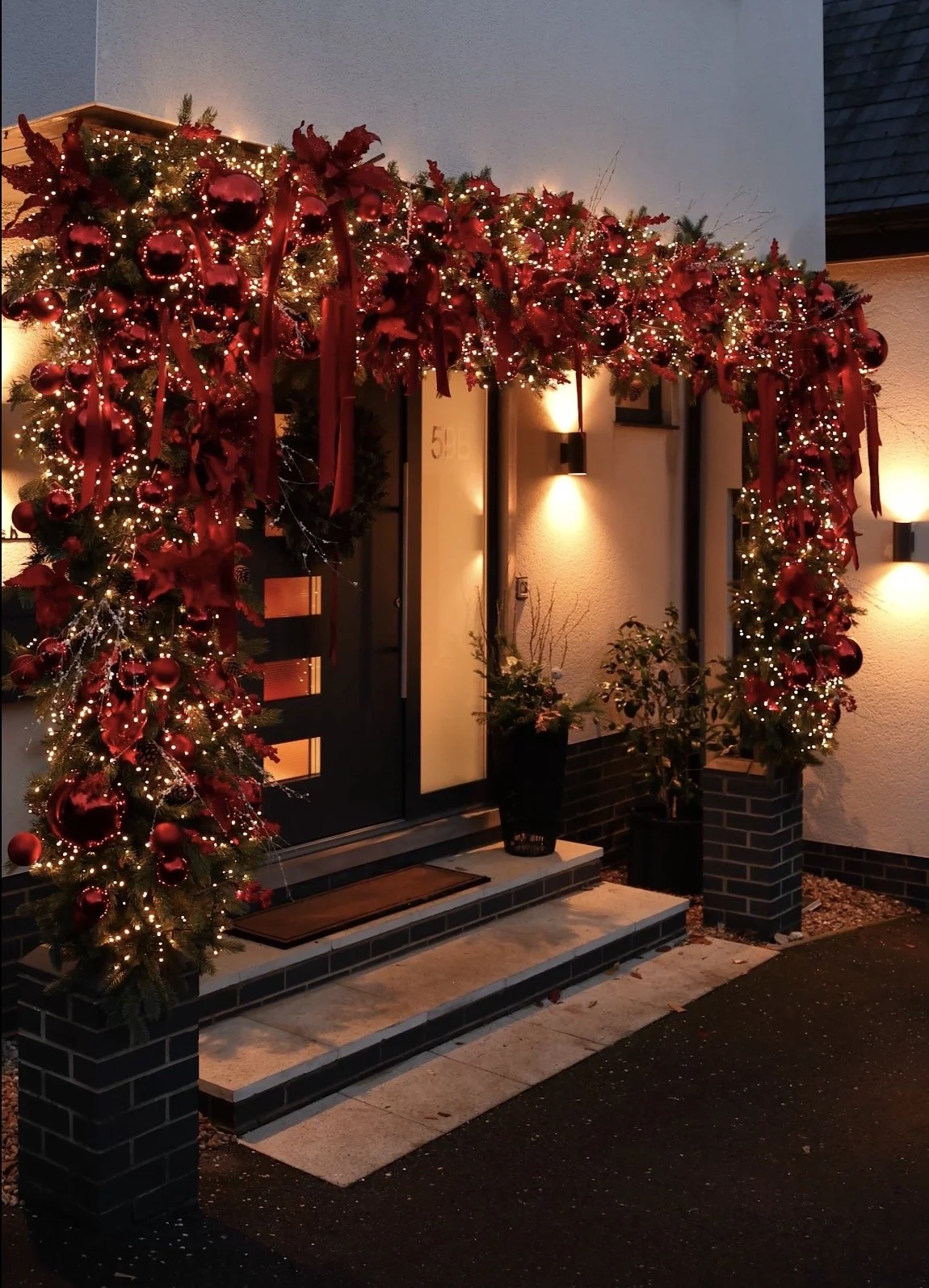 Christmas decorated front porch with red ornaments, ribbons, and string lights.