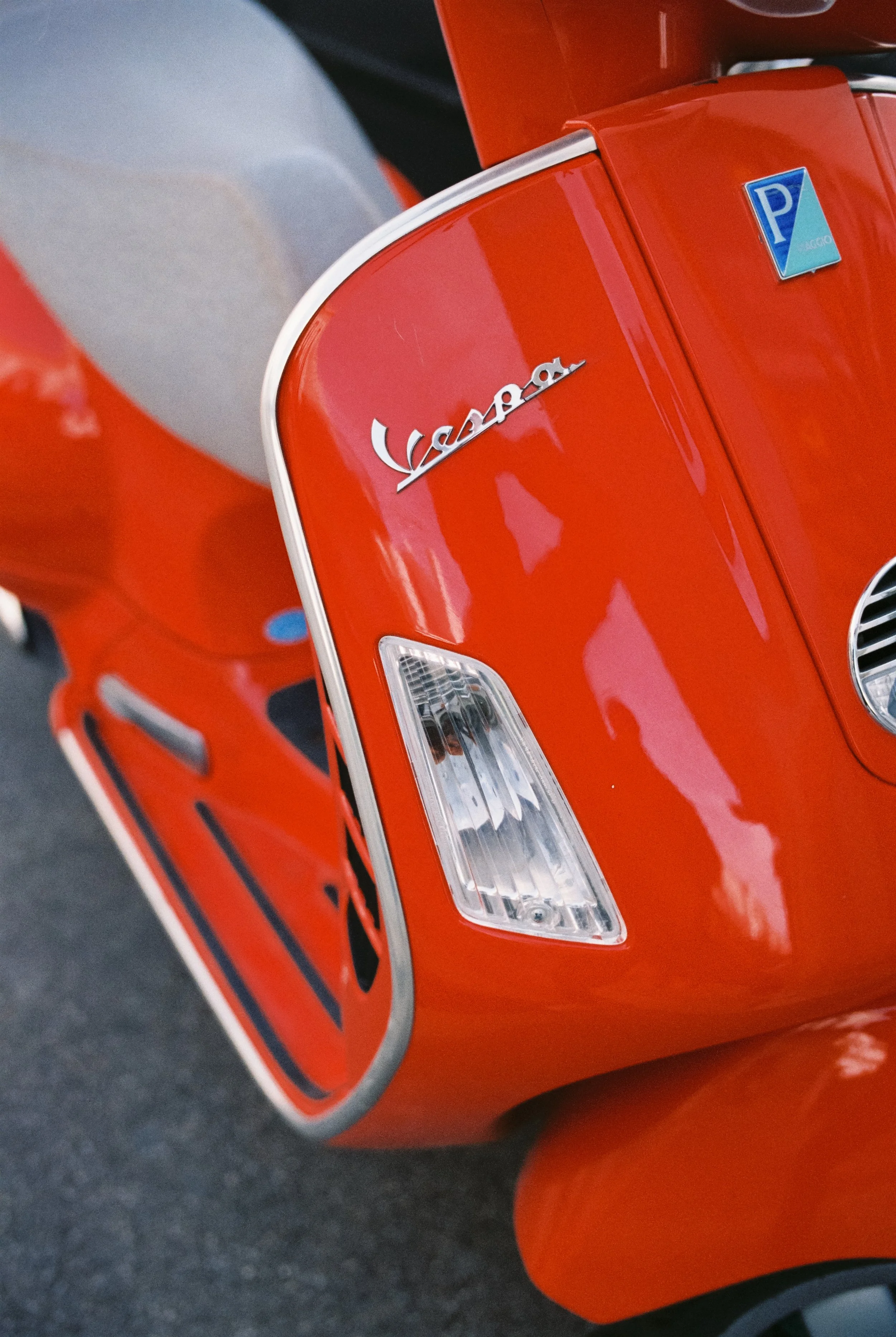 Ein roter Vespa-Roller mit silbernen Akzenten und einem Vespa-Logo auf der Motorhaube. Der Eindruck entsteht, dass es sich um ein Retro-Design handelt.