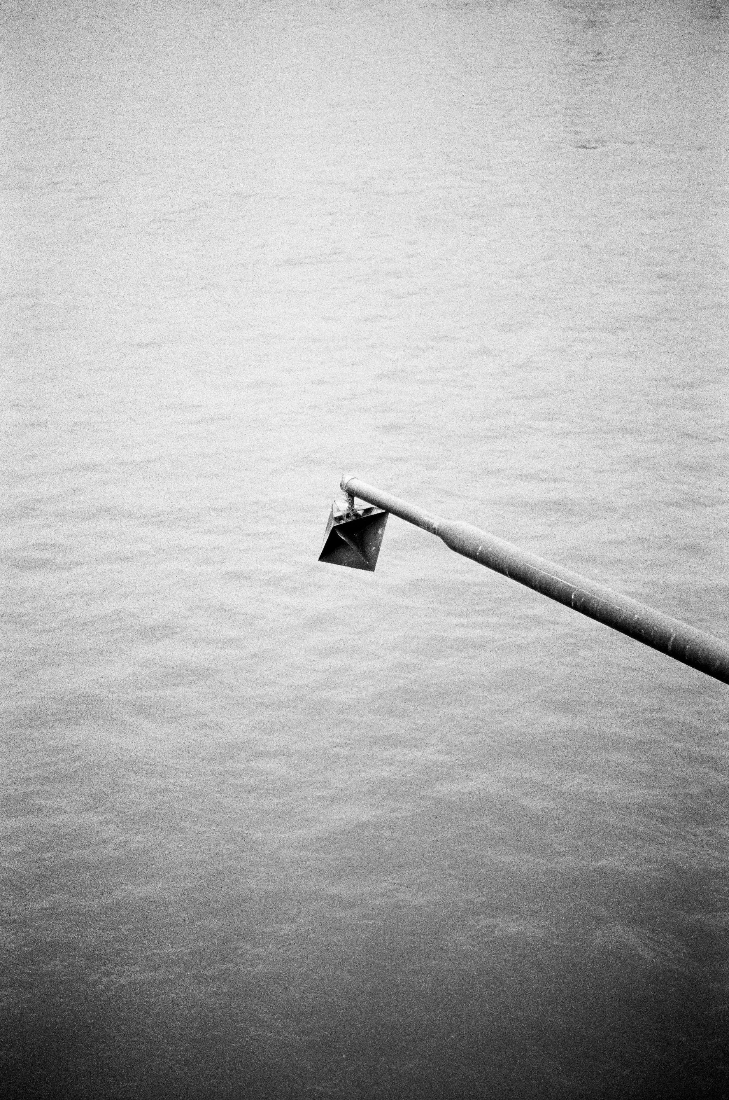 Schwarze Tauchlampe an einem langen Rohr über Wasser, schwarz-weiß