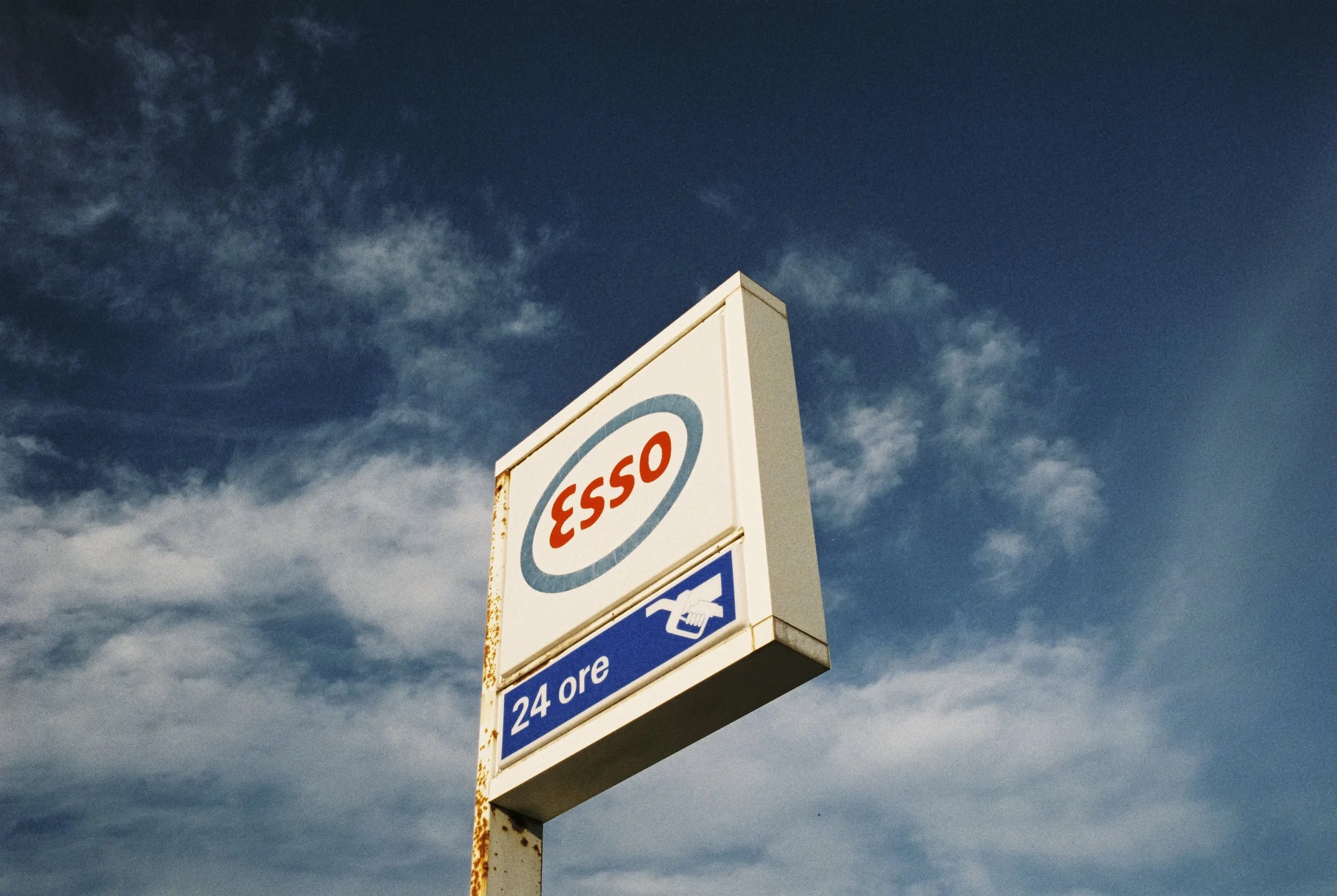 Tankstelle mit Esso-Logo und einem Hinweis auf 24 Stunden Öffnungszeit gegen den blauen Himmel.