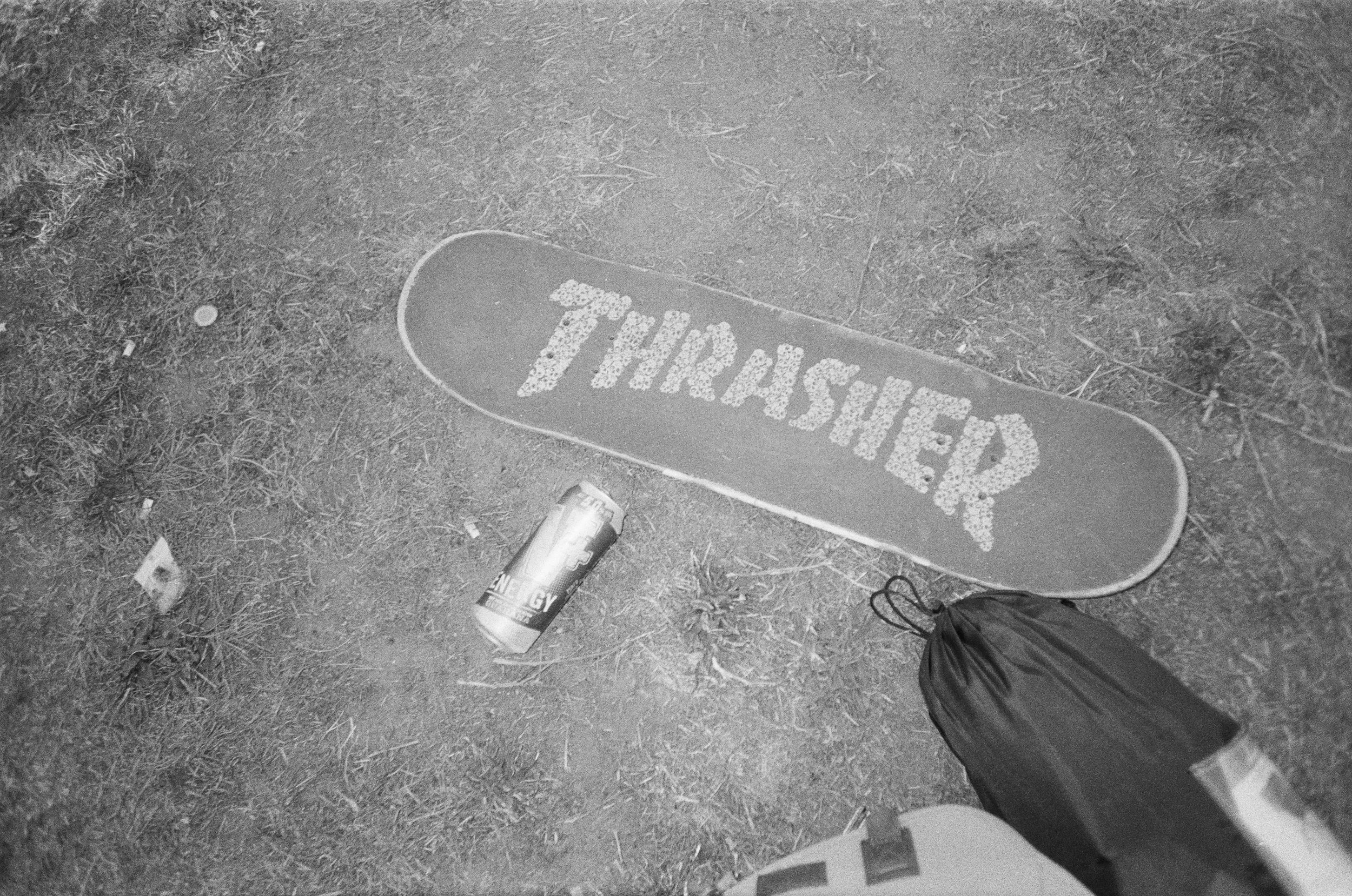 Auf dem Boden liegt eine Skateboard-Matte mit der Aufschrift 'THIRSTIED?', daneben eine Energy-Drink-Dose, eine Tüte und ein kleiner Gegenstand.