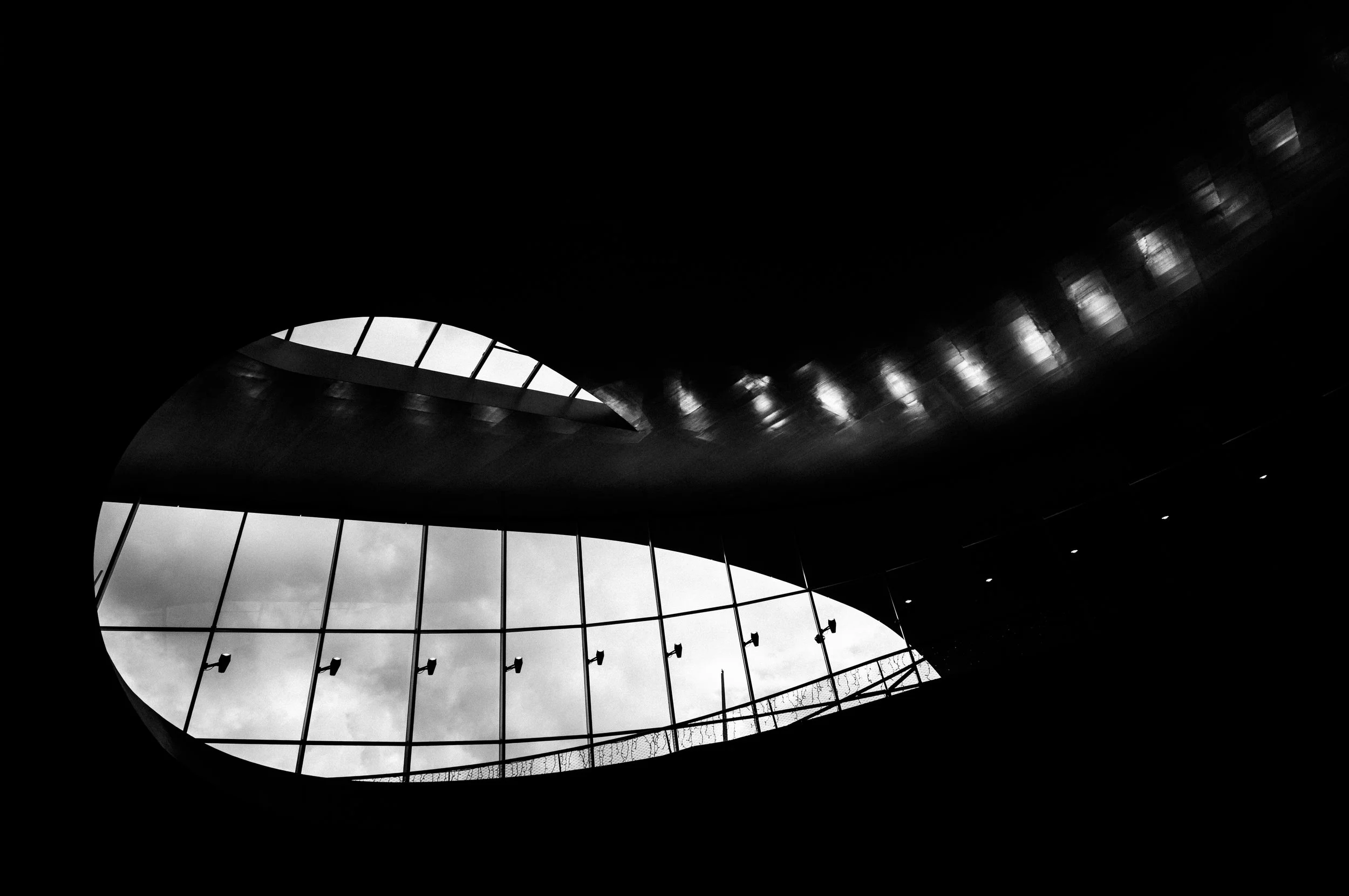 Dunkler Innenraum mit großer Fensteröffnung, die den Himmel zeigt, und Schatten auf dem Deckenbereich.