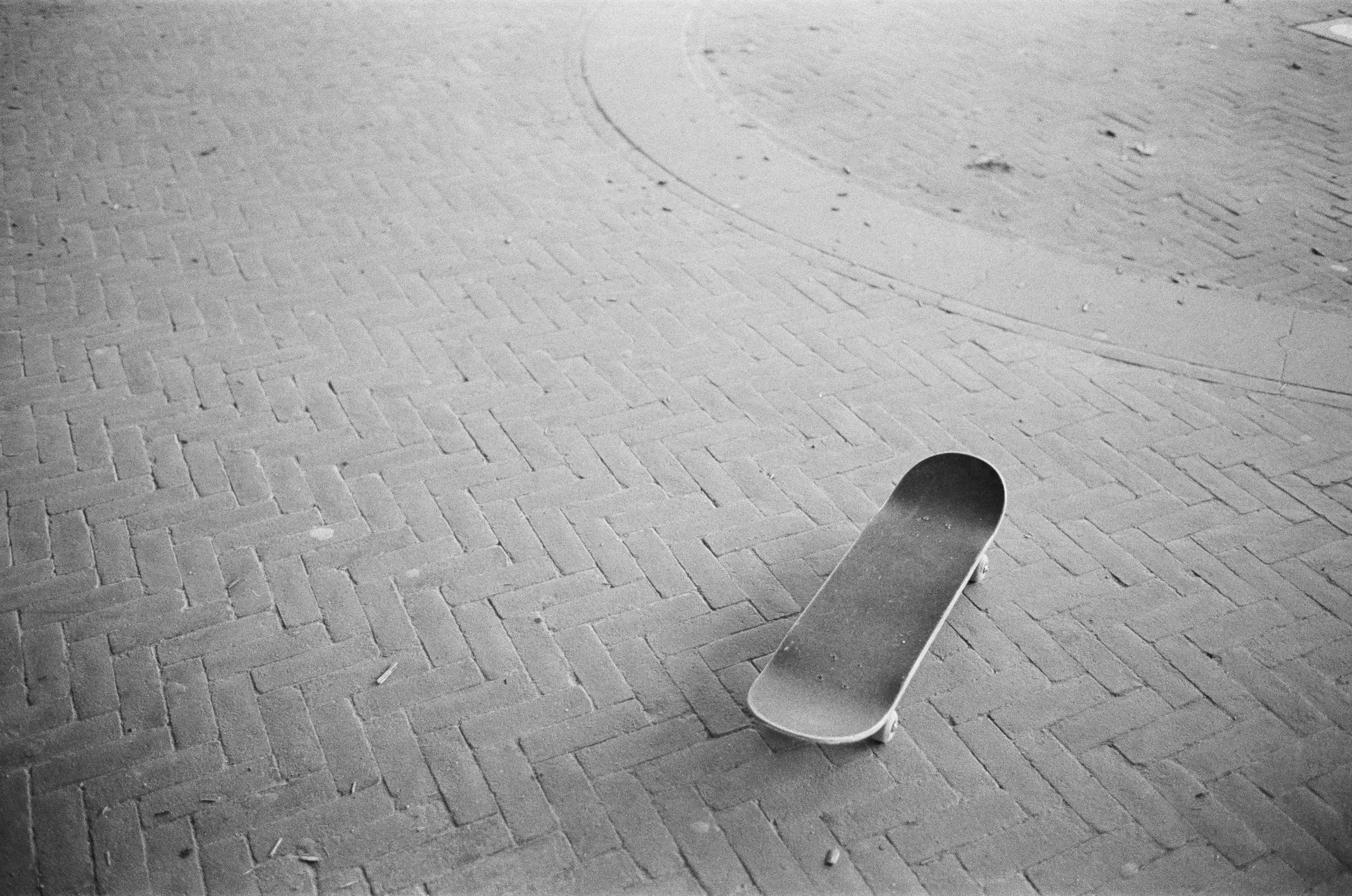 Leere Skateboard liegt auf einem gepflasterten Boden, keine Personen im Bild.