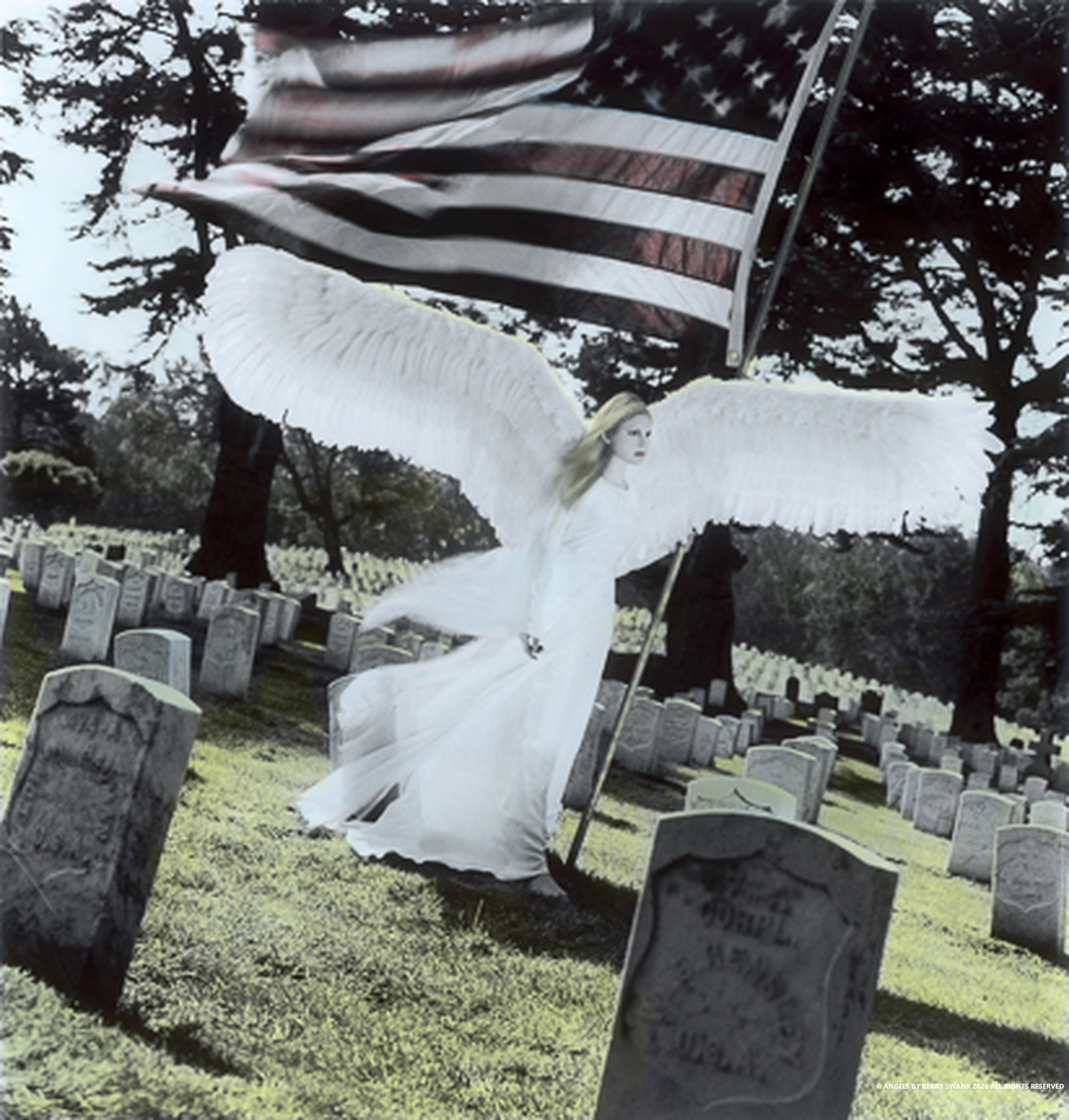 A statue of an angel with large white wings, holding an American flag in a cemetery with gravestones and trees in the background.
