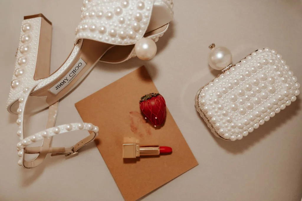 Damentasche, Schuhe, Lippenstift, Erdbeere, Lippen und Tasche mit Perlen, allée mit Perlen, auf einer weißen Oberfläche