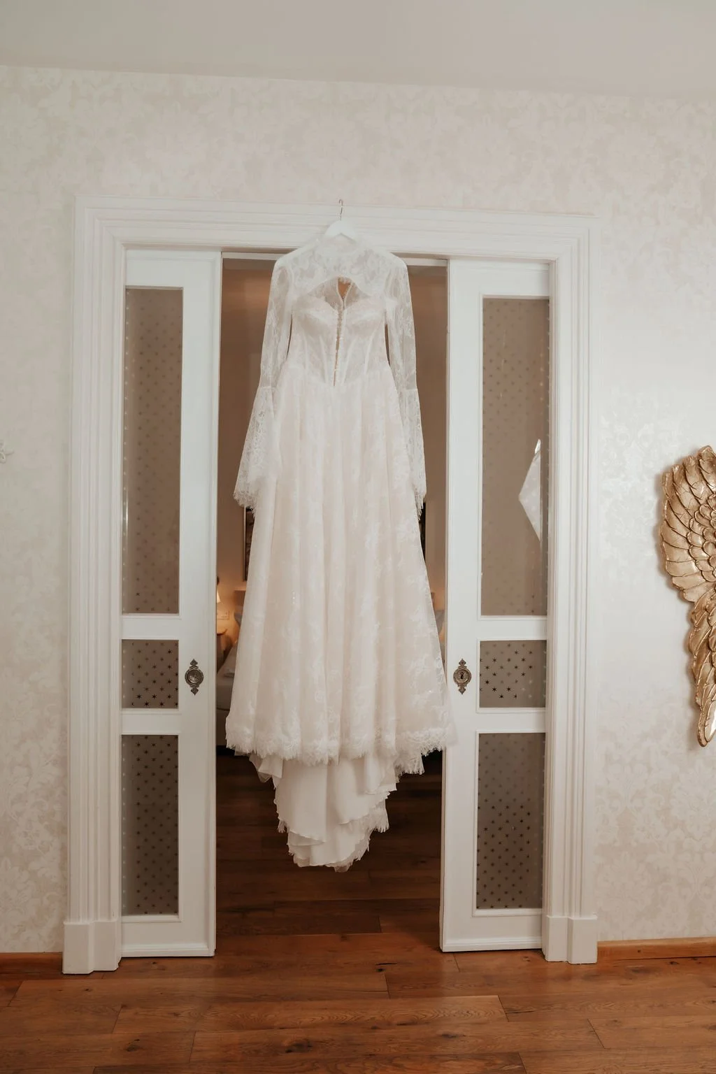 Ein weißes Brautkleid hängt an einem weißen Türrahmen.