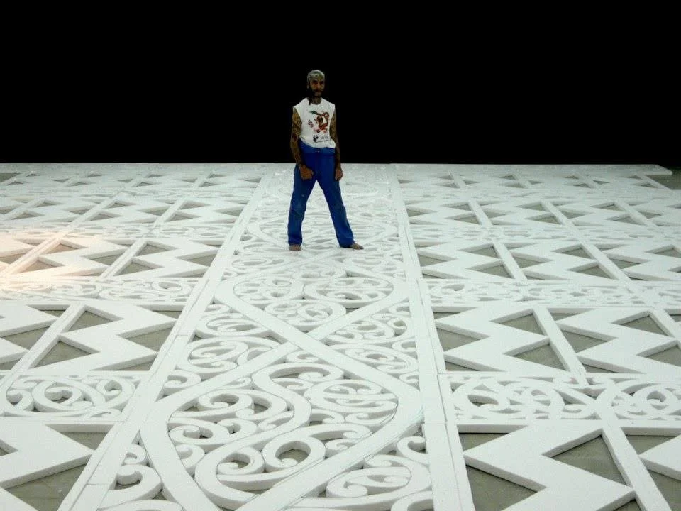 Person standing on a decorative white lattice platform against a black background.
