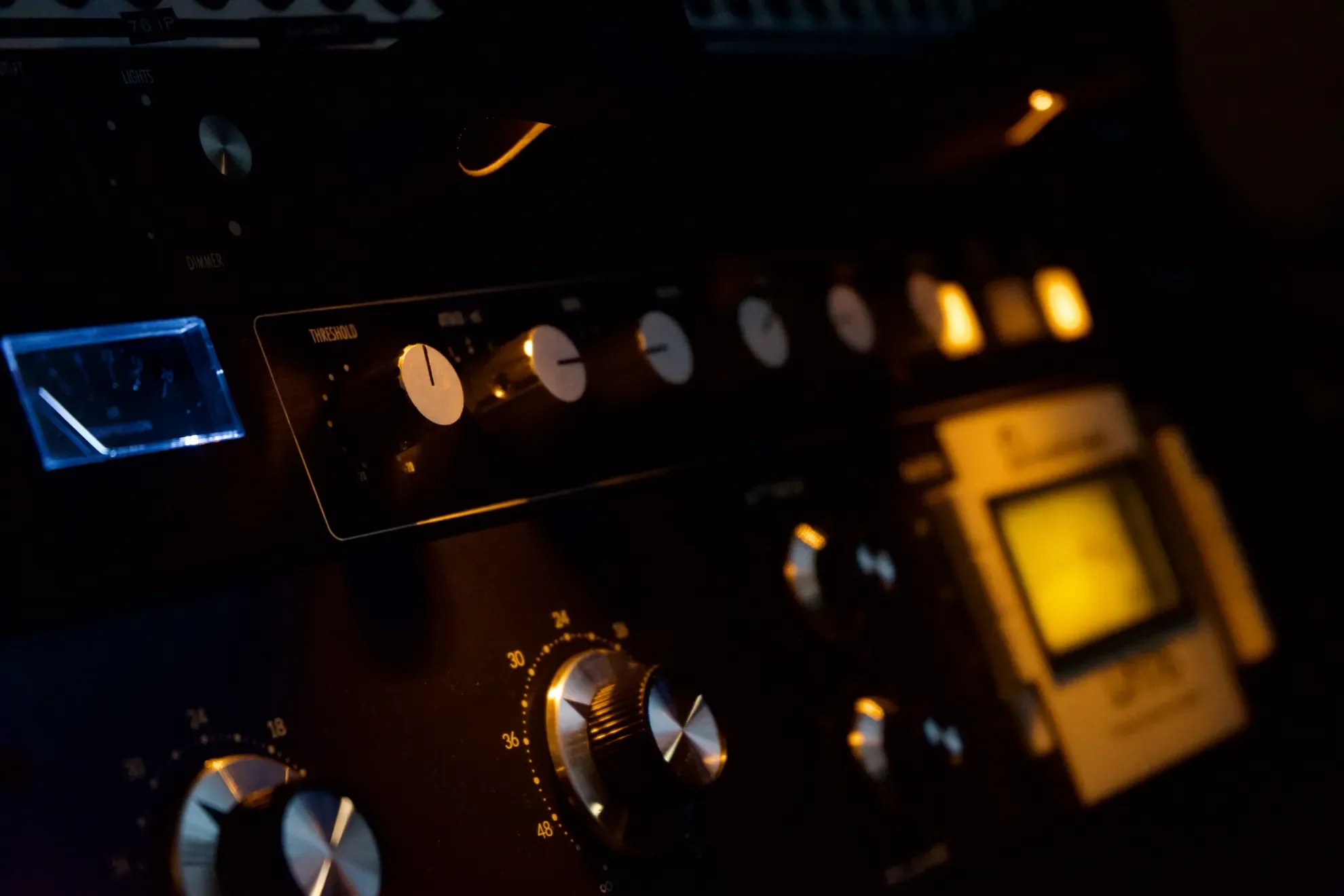 Close-up of a car radio and climate control system illuminated in warm yellow and blue lighting