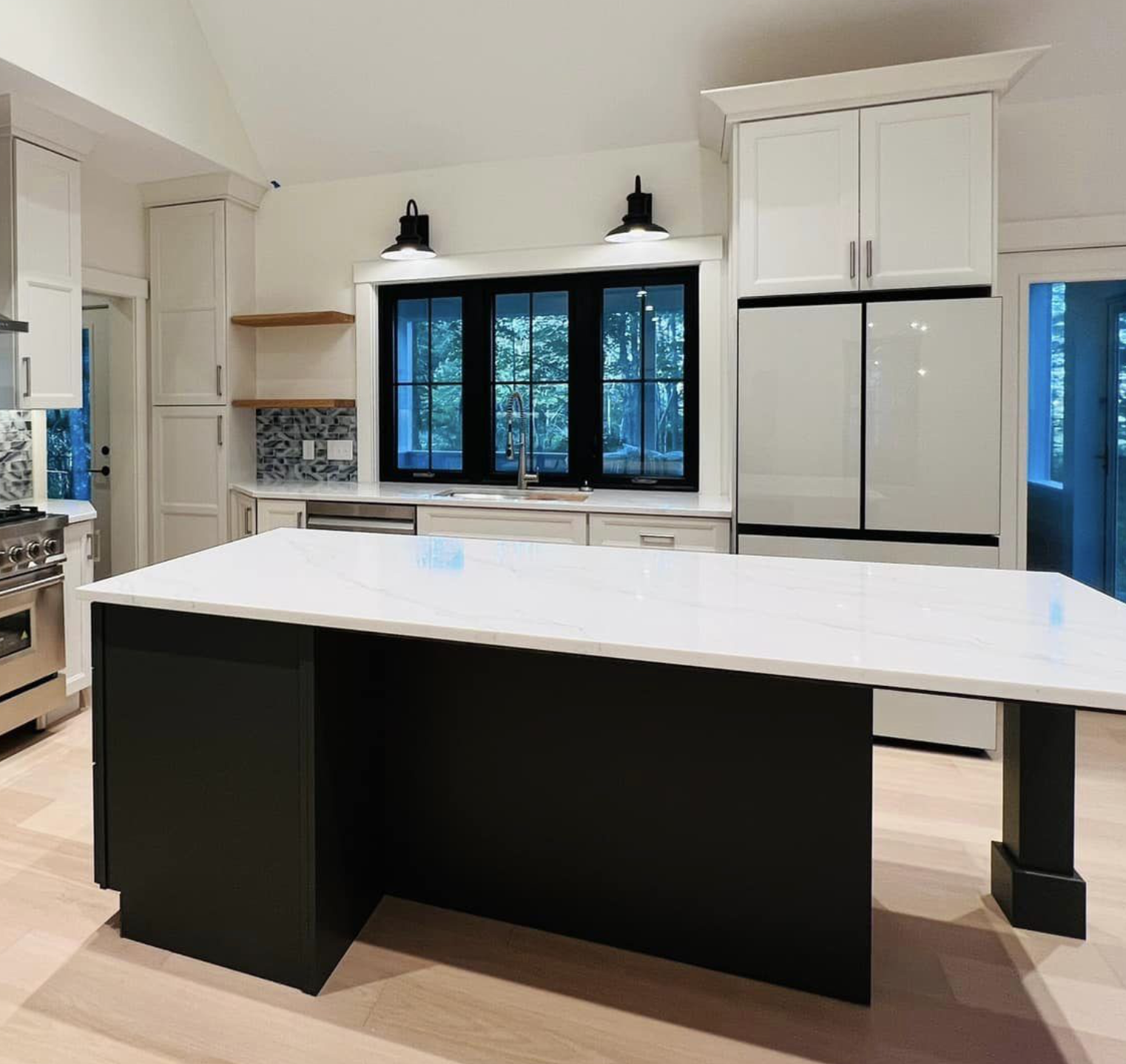 Modern kitchen with white cabinetry, black window frames, and a large island with a white countertop and black base.