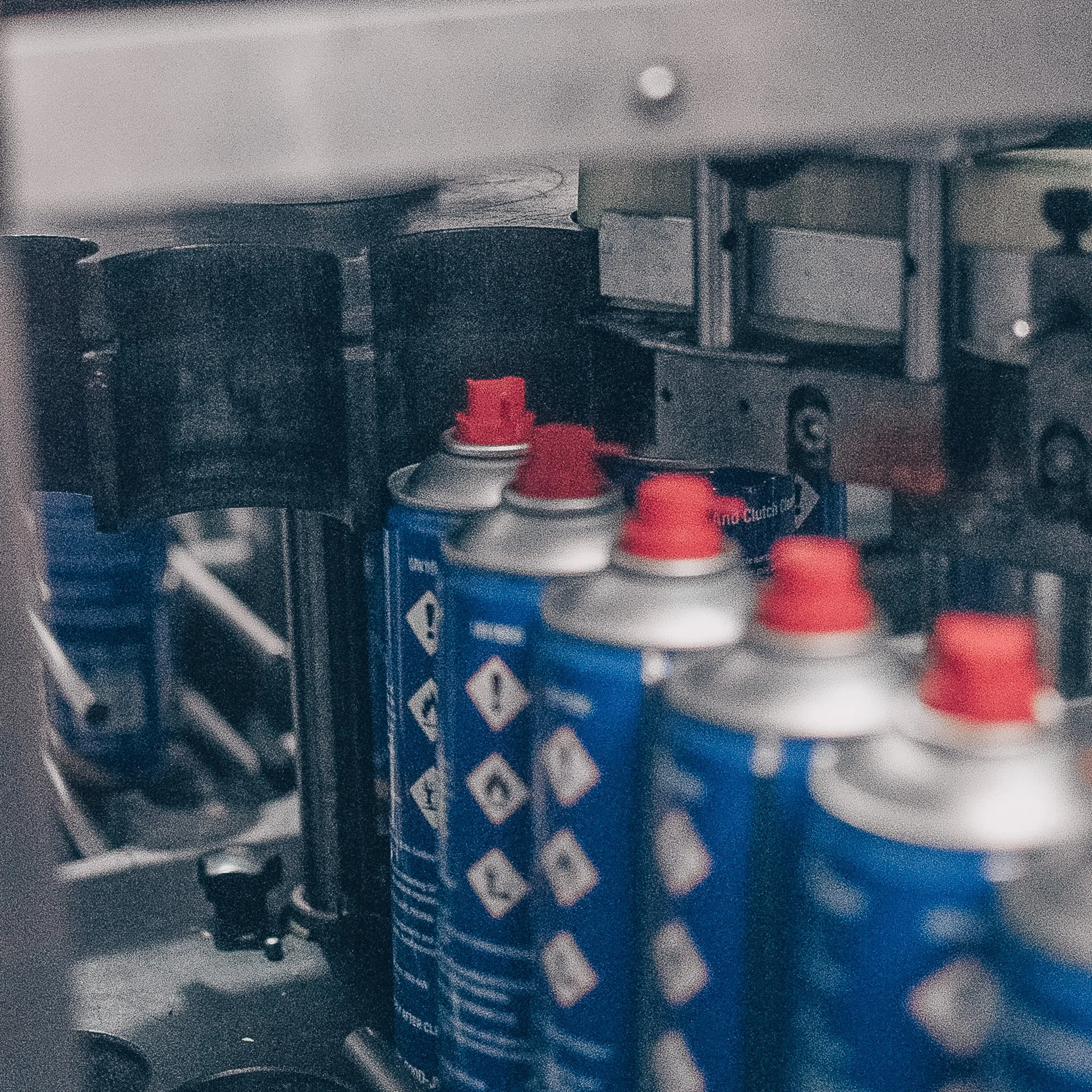Blue Aerosol Cans with Red Buttons in Machine