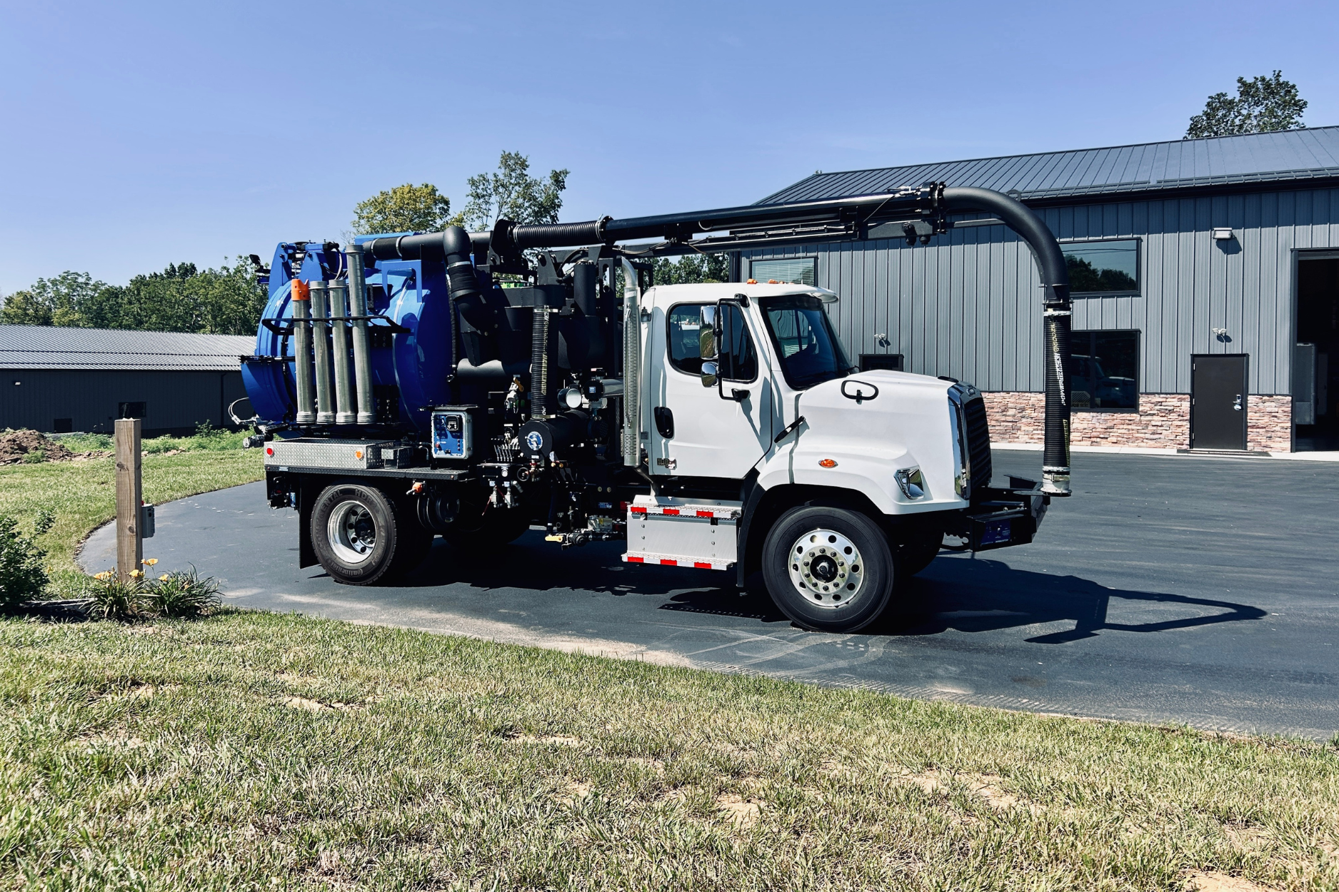 A small blue and white PipeHunter Hydro-X compact vacuum truck, parked on a paved surface in front of the 502 Equipment service center in LaGrange, KY.