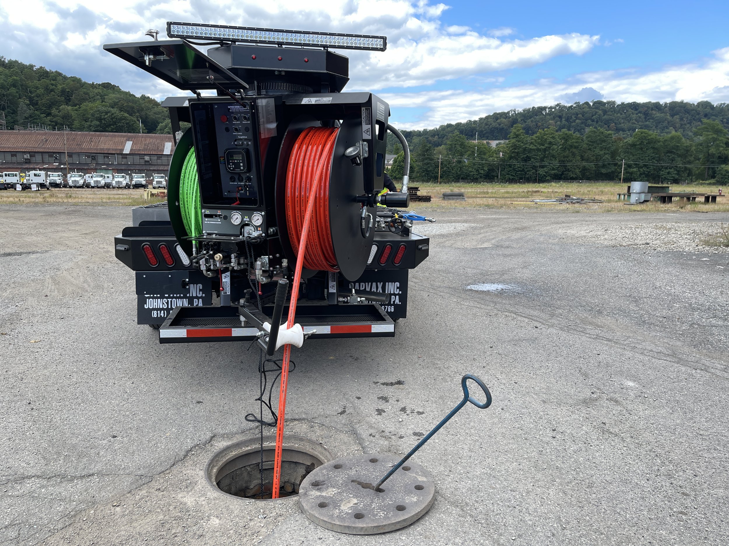 The gapvax g7t, a powerful truck mounted jetter with 2 sizes of hose reels is working as an orange hose enters a manhole in Nashville, Tn