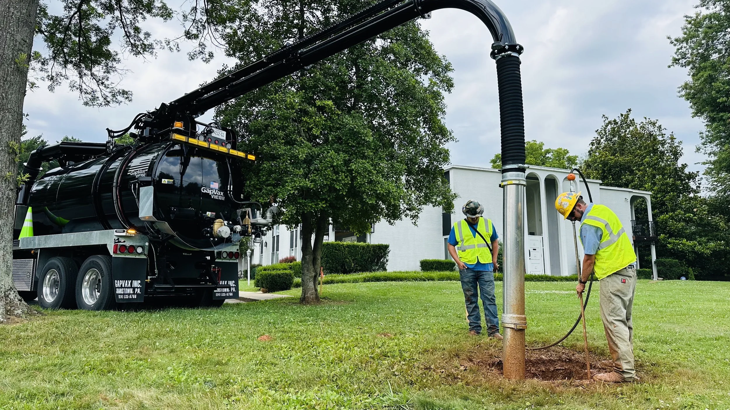 Workers in safety vests and helmets identifying a water leak using a gapvax vacuum truck in bloomington, indiana. 