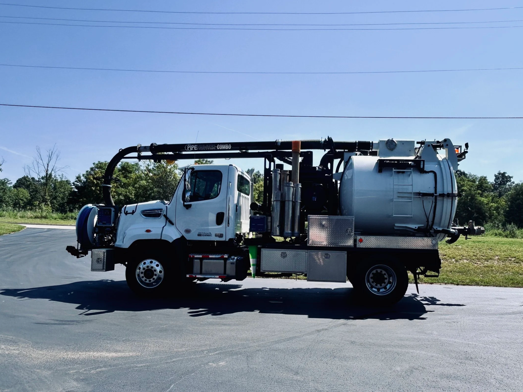 A small industrial vacuum truck, a PipeHunter mini combo truck parked on a paved surface with trees and power lines in the background at the 502 Equipment Service center near lagrange, ky.