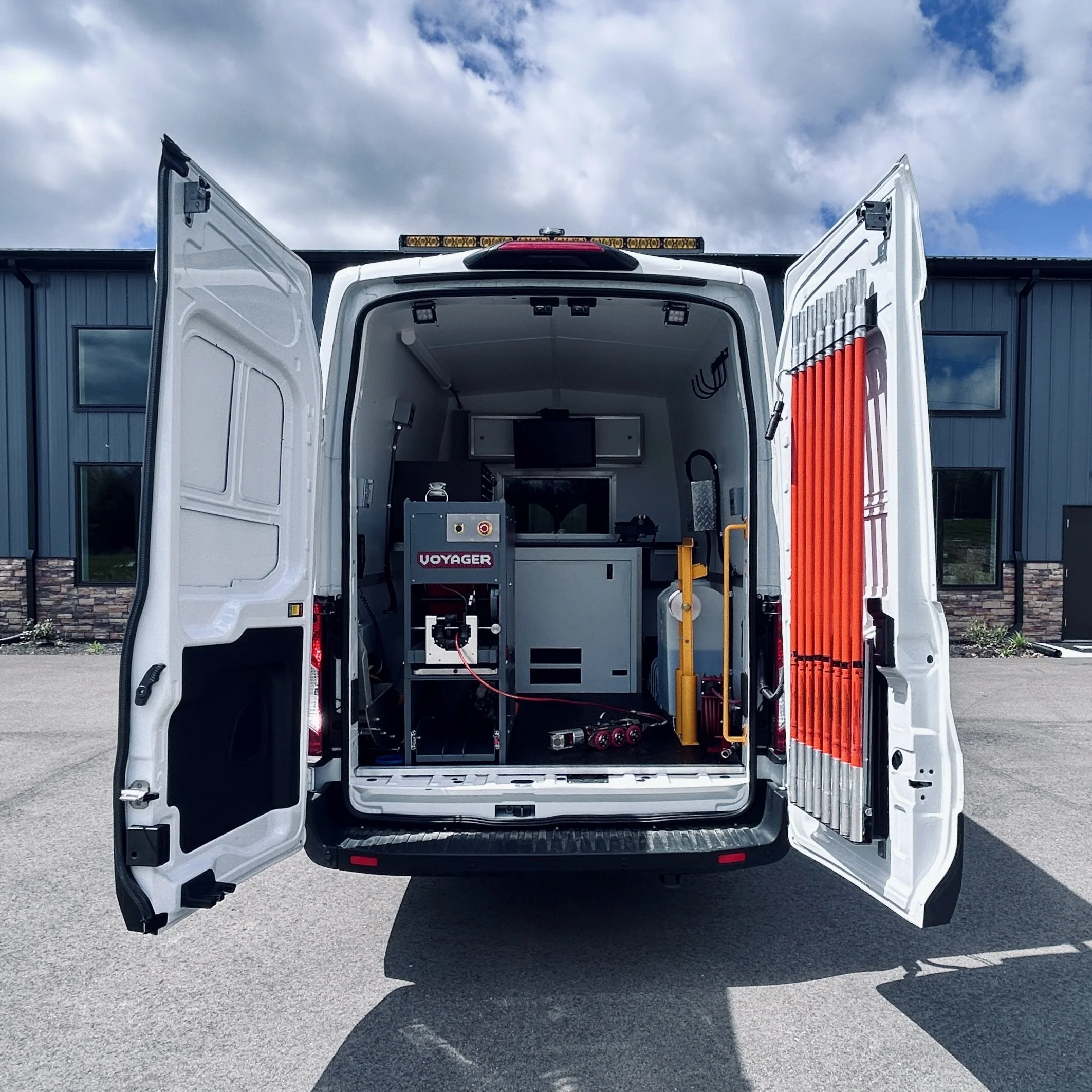 The back of a white utility van with the doors open, showing the Aries Voyager pipe inspection system.