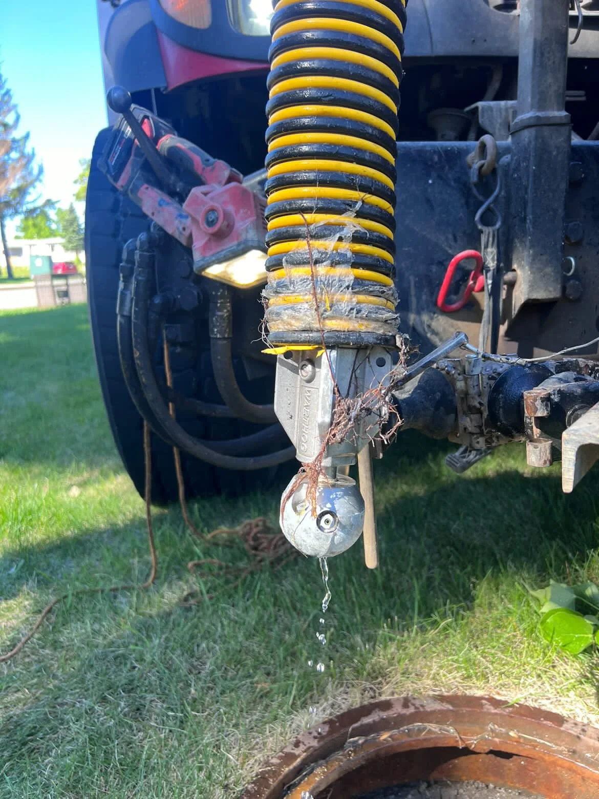 Close-up of a vacuum truck hose reel with Warthog sewer nozzle, sold by 502 equipment in Kentucky, Indiana and Tennesse attached over a manhole.
