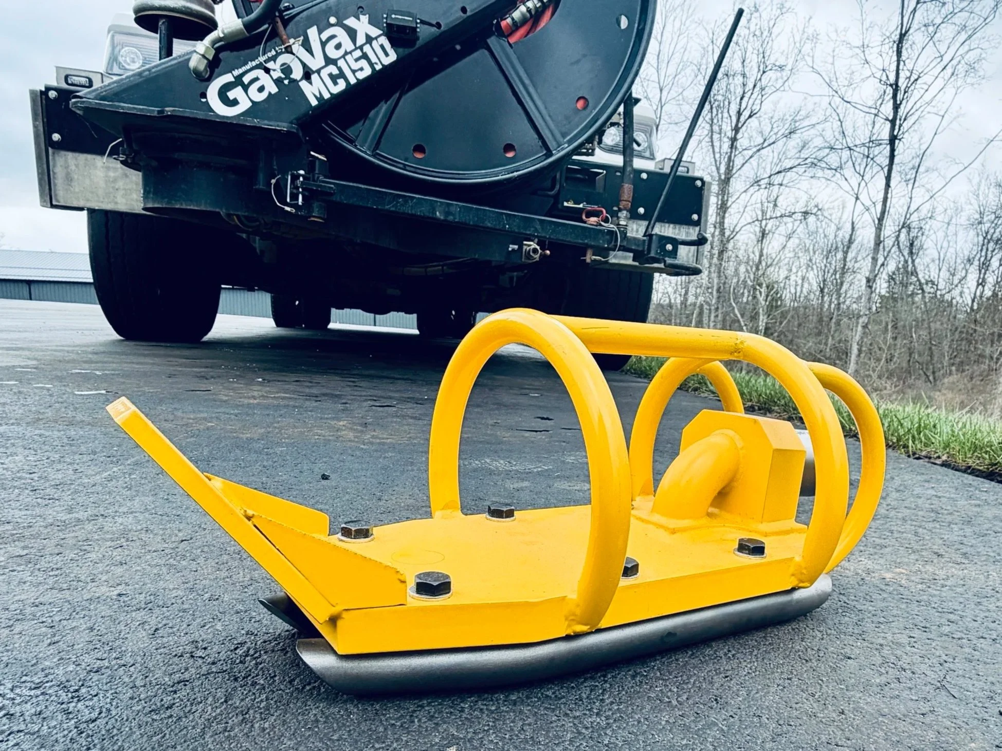 A yellow warthog bulldozer sled nozzle in front of a gapvax mc vacuum truck. 