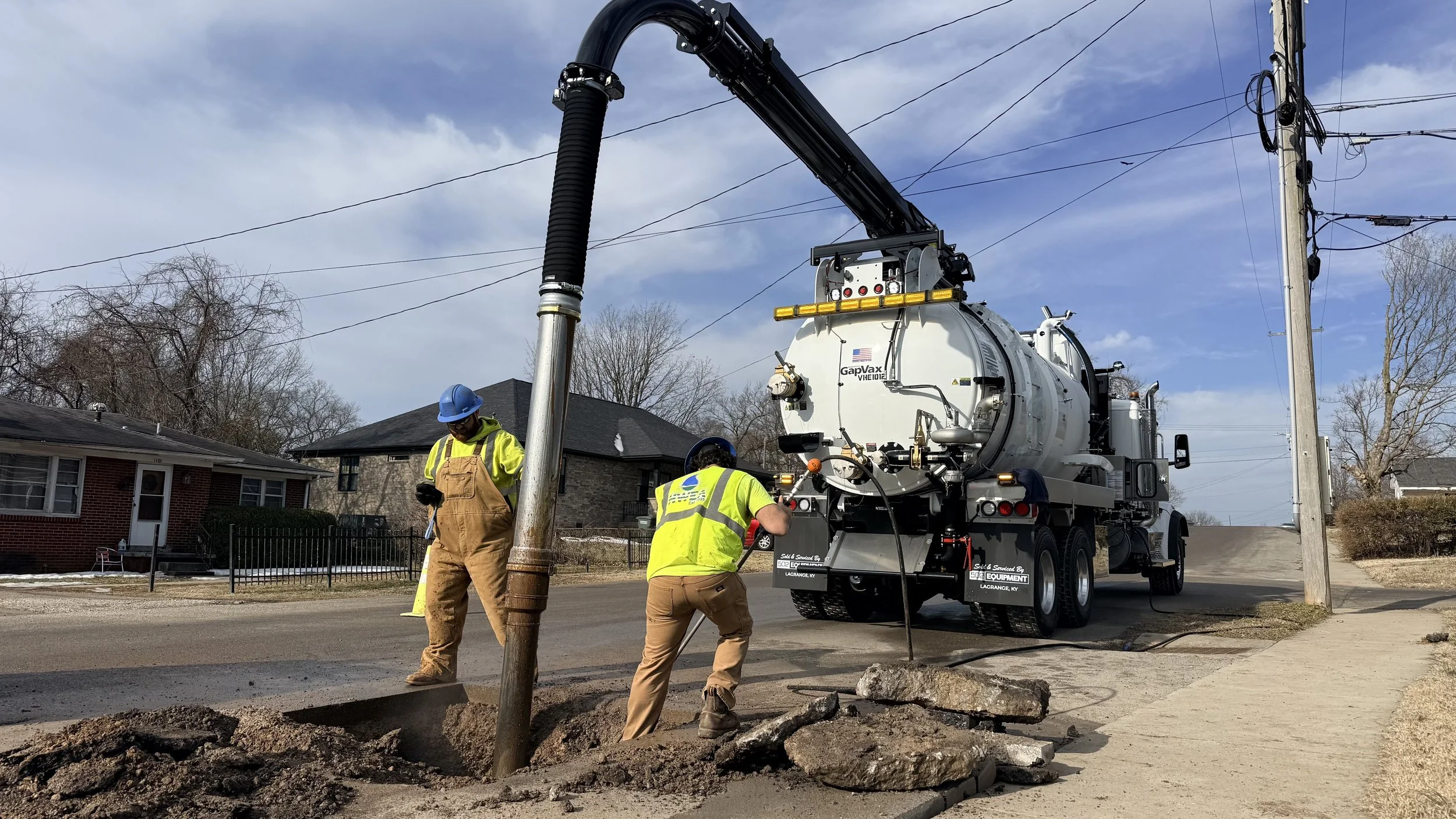 2 Municipal workers  in safety gear using a GapVax VHE vac truck to repair a water line break near Bloomington, Indiana.