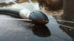 A Red Dawg low pro nozzle laying on the ground connected to a vacuum truck hose. 