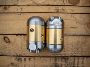 Two sewer jetting nozzles with gold and silver coloring on a wooden surface.