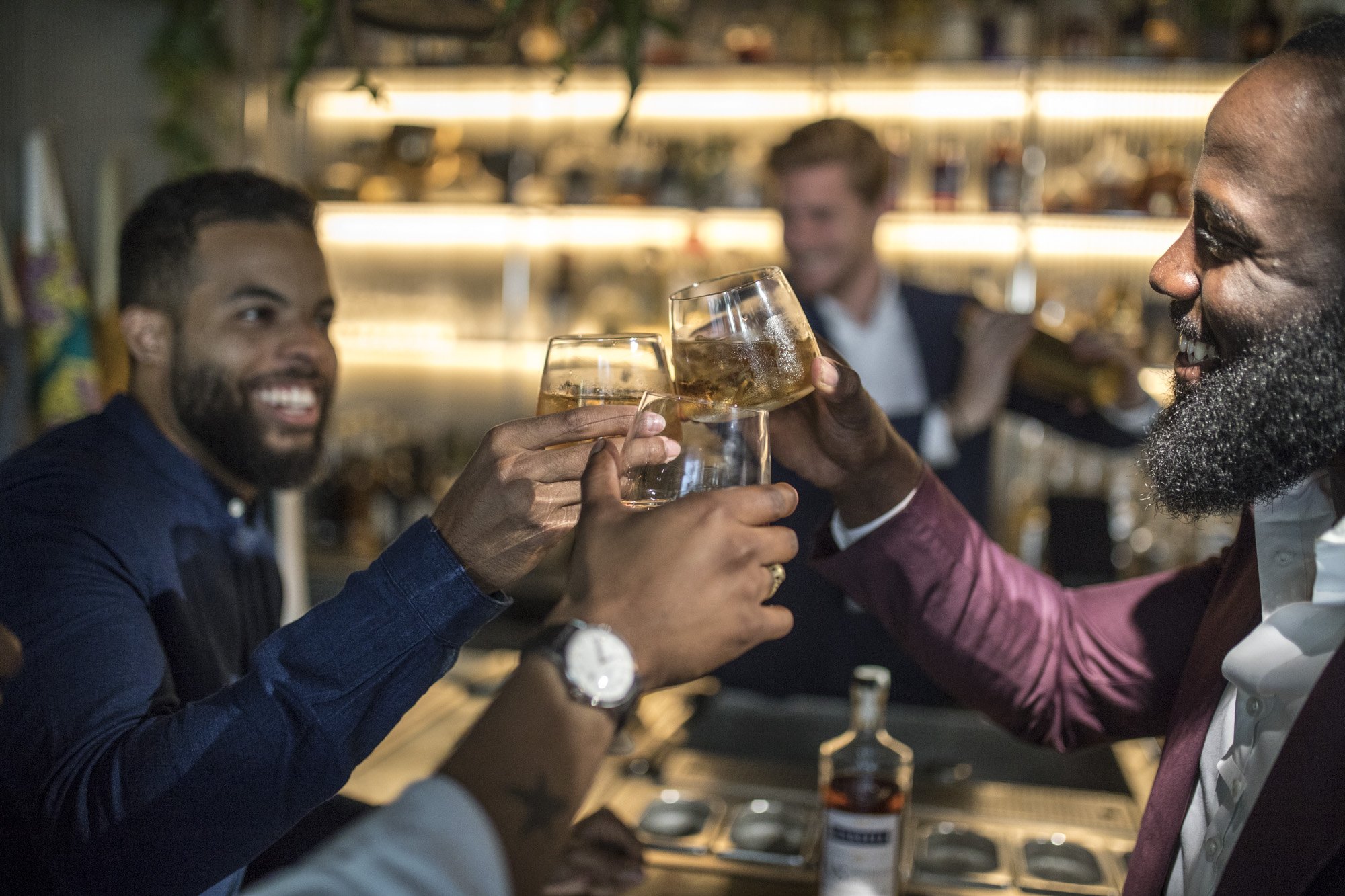 Groupe d'amis faisant un toast avec des verres de boisson dans un bar.