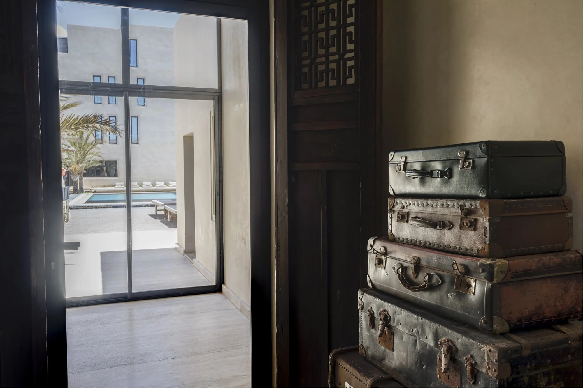 Pièces de valise empilées dans une pièce avec une vue sur la cour extérieure et la piscine