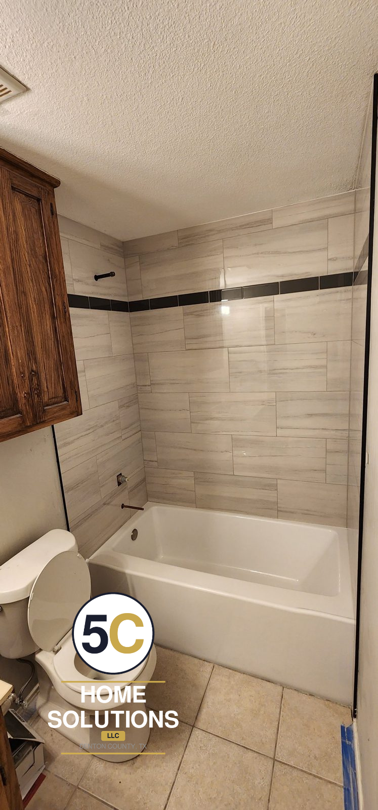 After: new bathtub with floor-to-ceiling plank tile and black accent stripe by 5C Home Solutions, Denton County TX