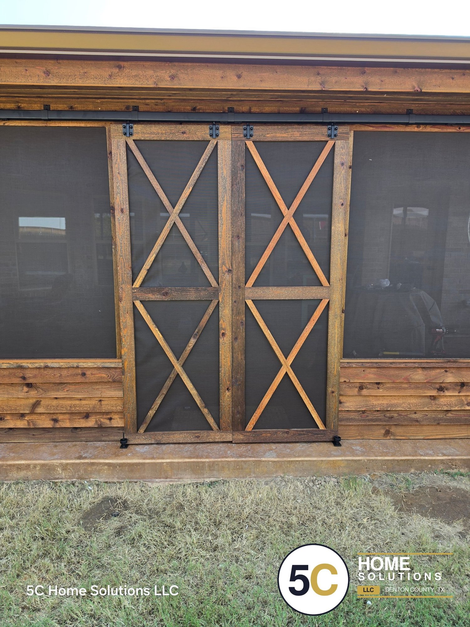 Custom double sliding cedar barn door screen doors on a screened patio