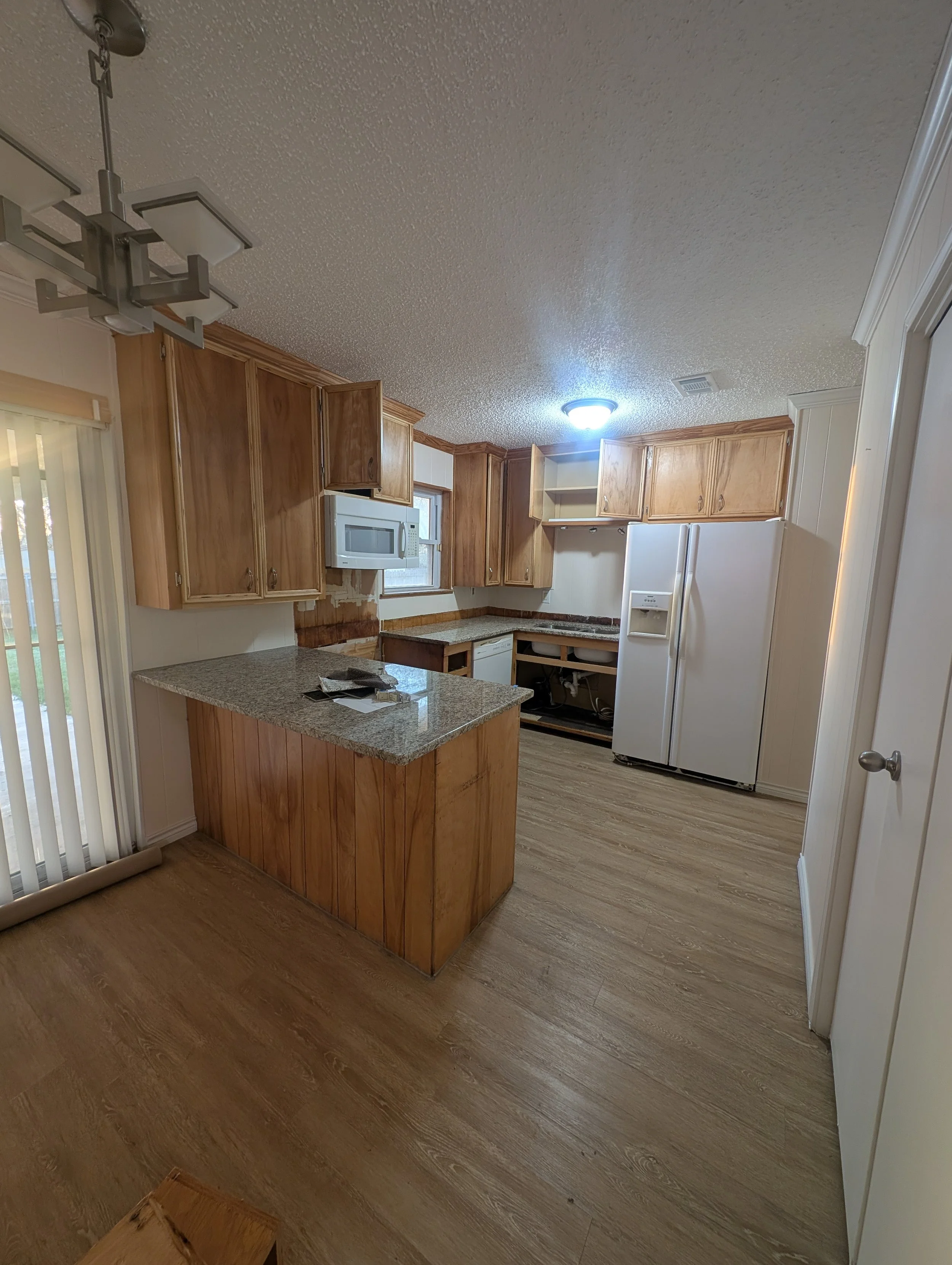 Dated oak kitchen cabinets before professional painting in Denton, TX. Worn finish and missing hardware made this kitchen a prime candidate for a cabinet painting upgrade.