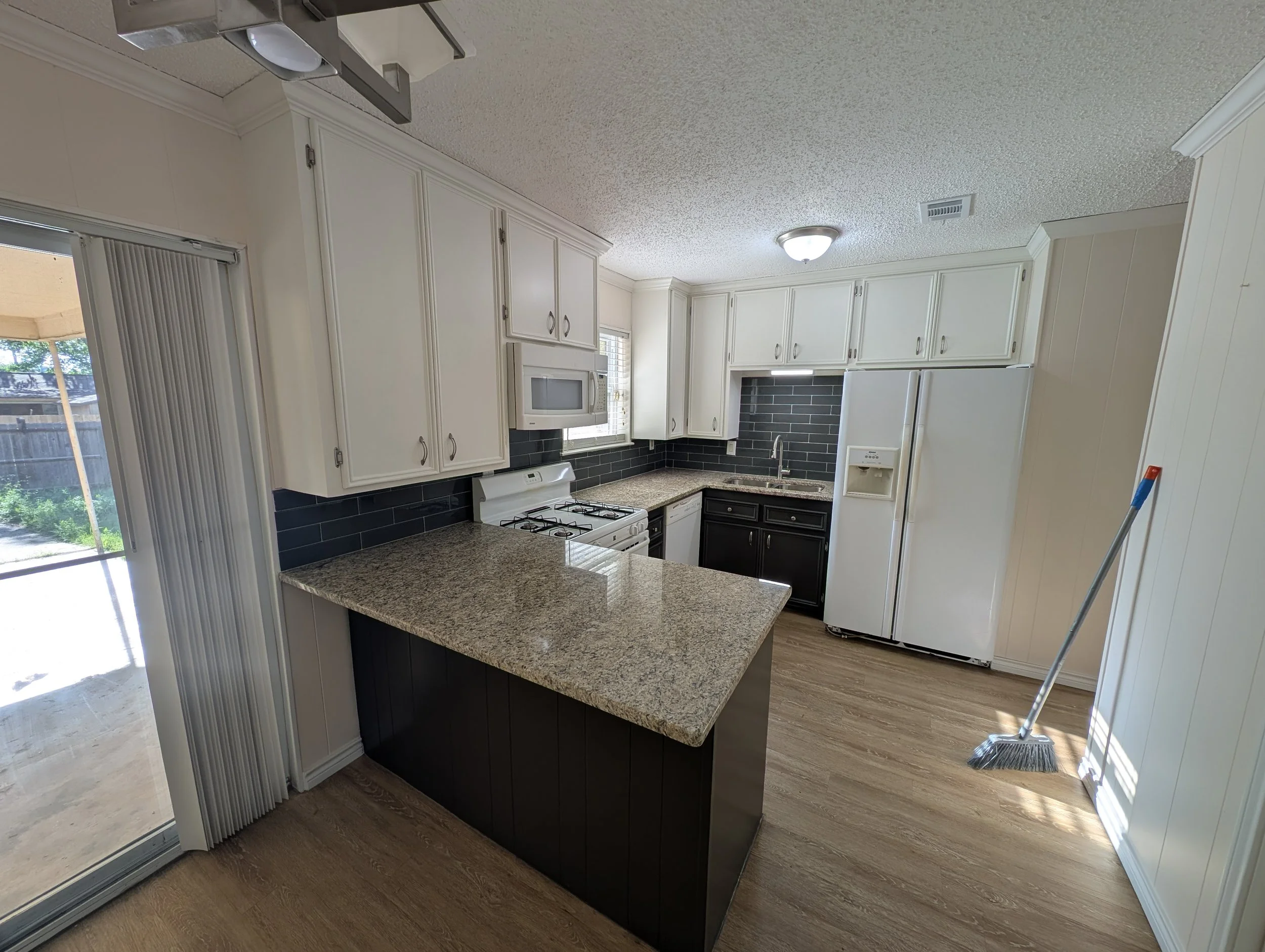 Two-tone kitchen cabinet painting in Denton, TX. White uppers and dark base cabinets with a new subway tile backsplash — a budget-friendly kitchen refresh by 5C Home Solutions.